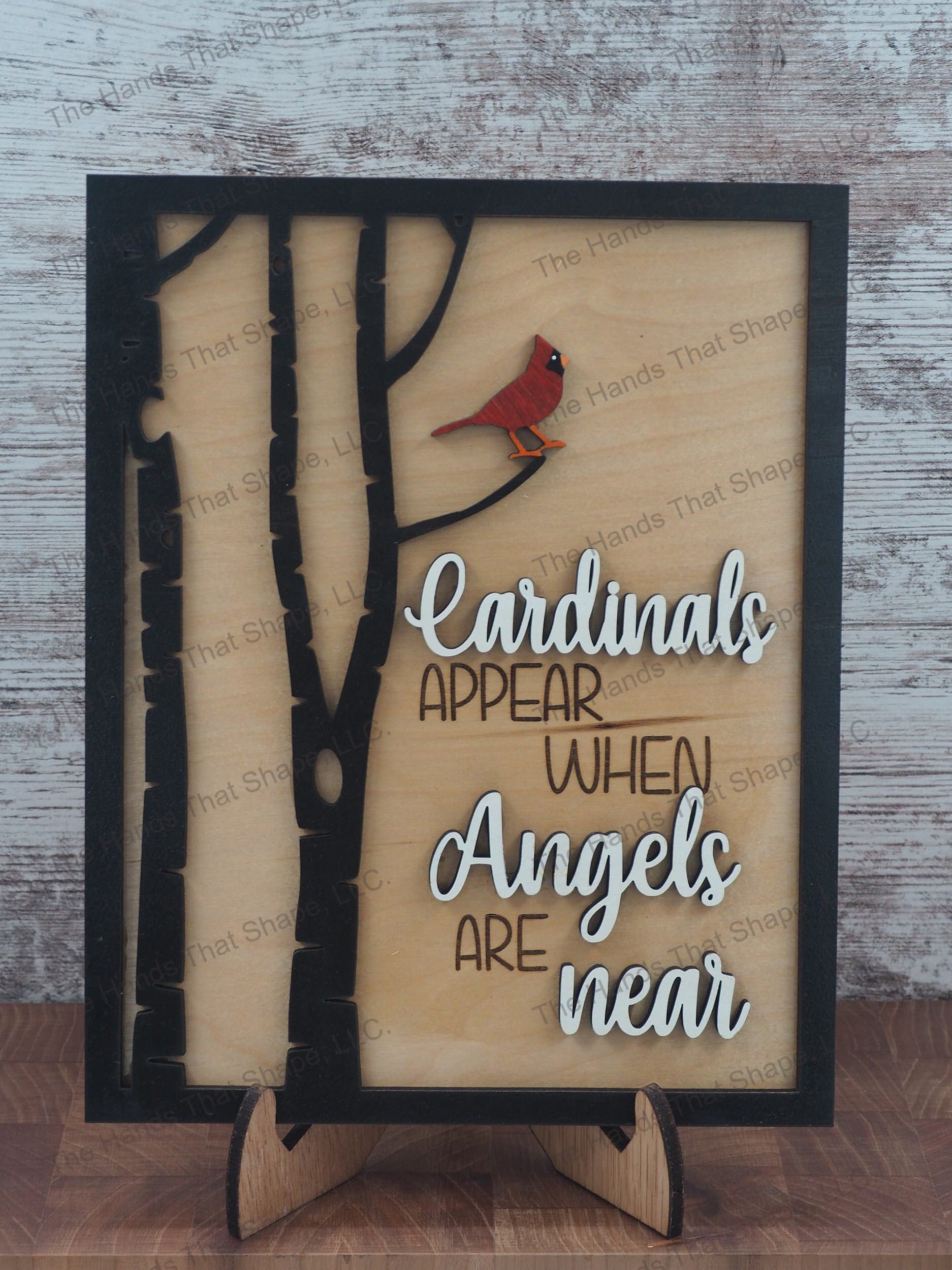 The ”Cardinals Appear” art features a red cardinal perched in a tree with an “when angels are near” saying in white.