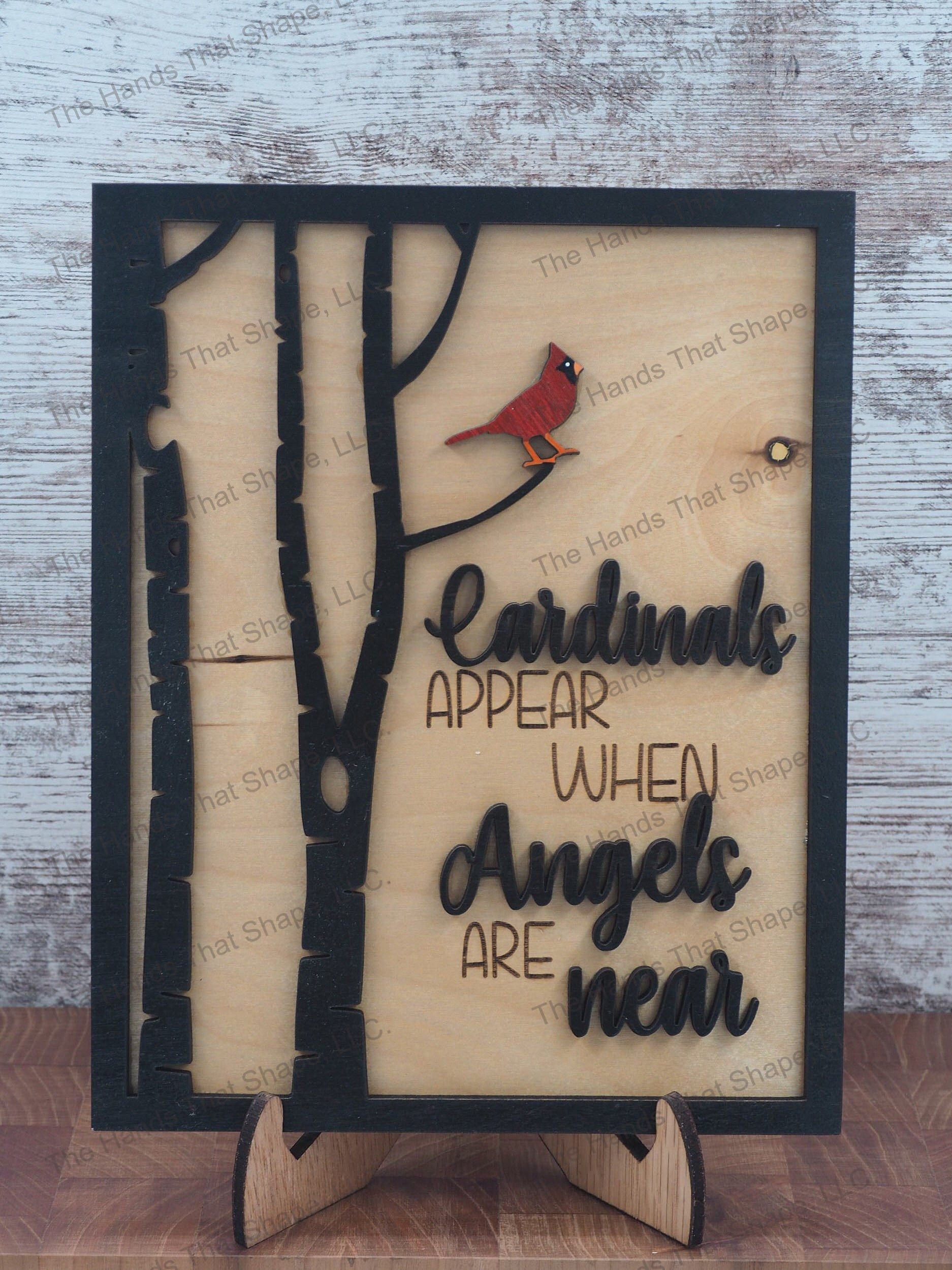 The ”Cardinals Appear” art features a red cardinal perched in a tree with an “when angels are near” saying in black.