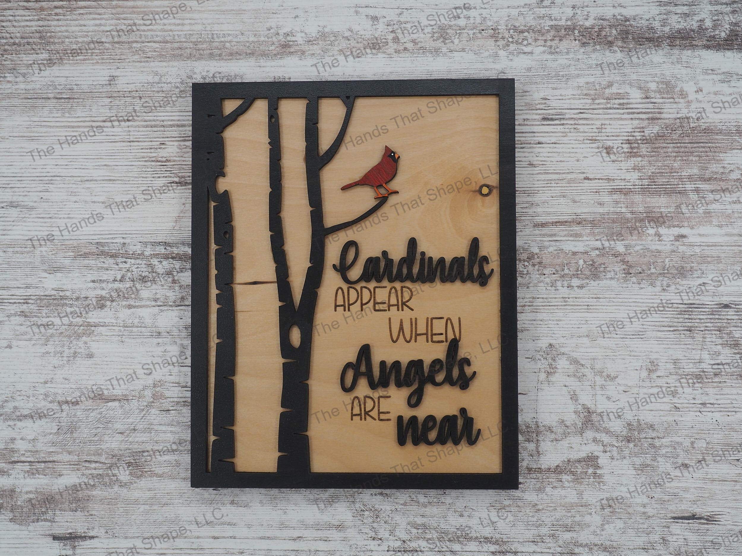 The ”Cardinals Appear” art features a red cardinal perched in a tree with an “when angels are near” saying in black.