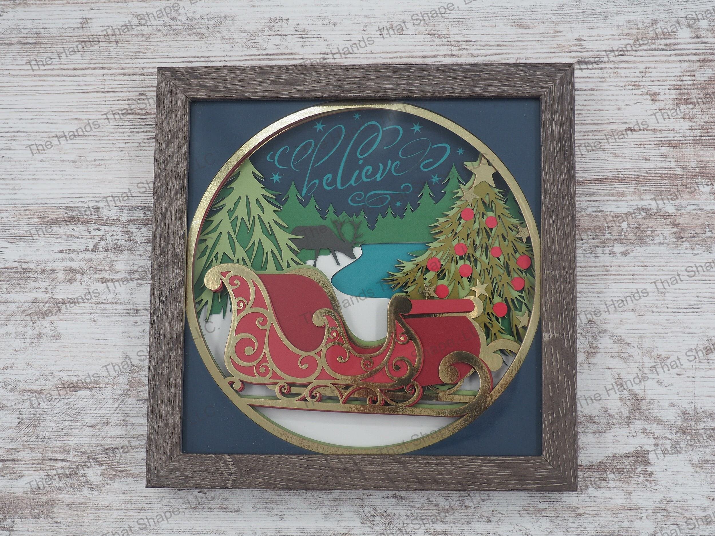 The shadow box features a forest of Christmas trees with Santa's reindeer taking a break, his sleigh fully decorated and the word "Believe" scrolled across the sky.