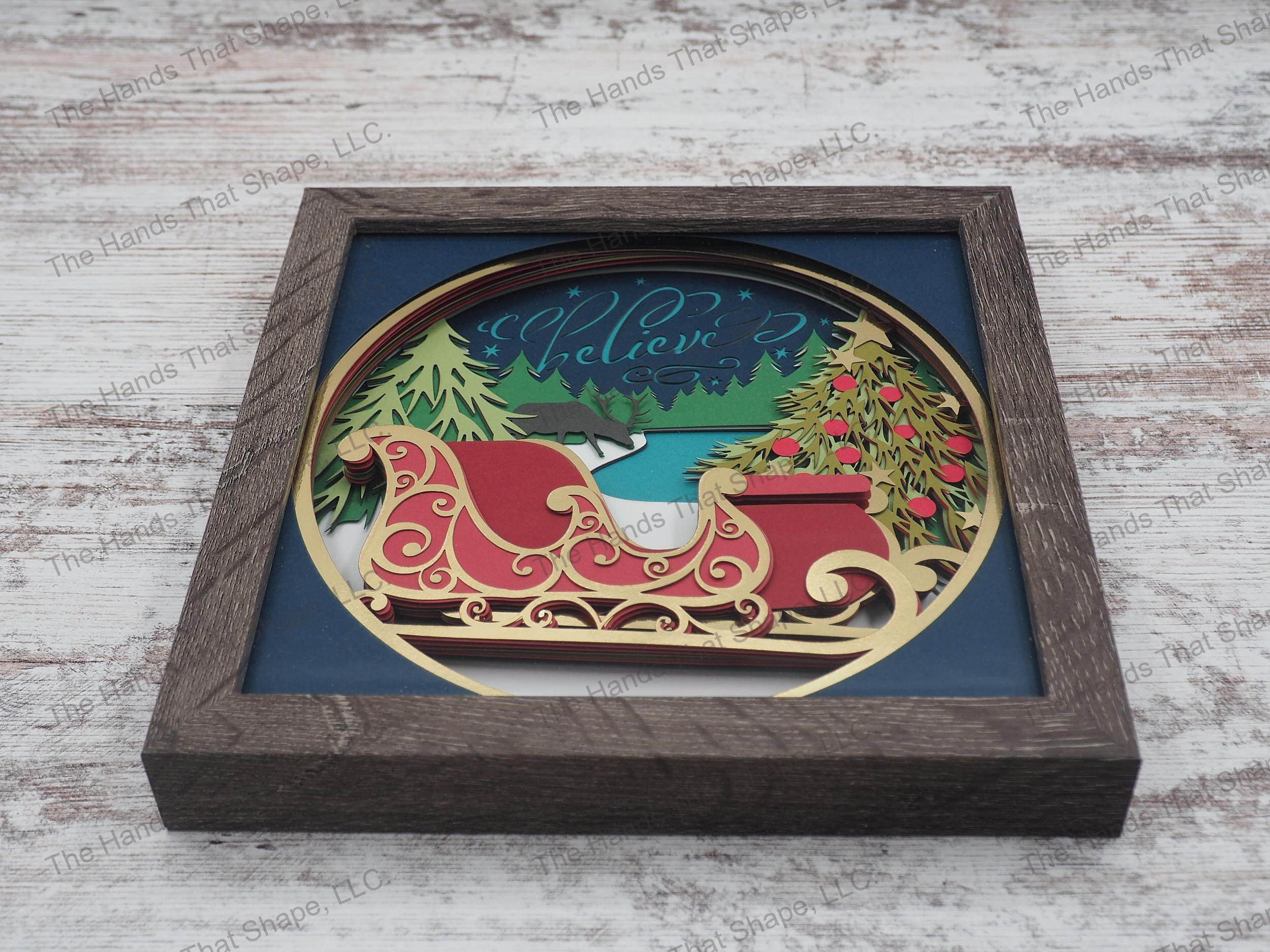 The shadow box features a forest of Christmas trees with Santa's reindeer taking a break, his sleigh fully decorated and the word "Believe" scrolled across the sky.