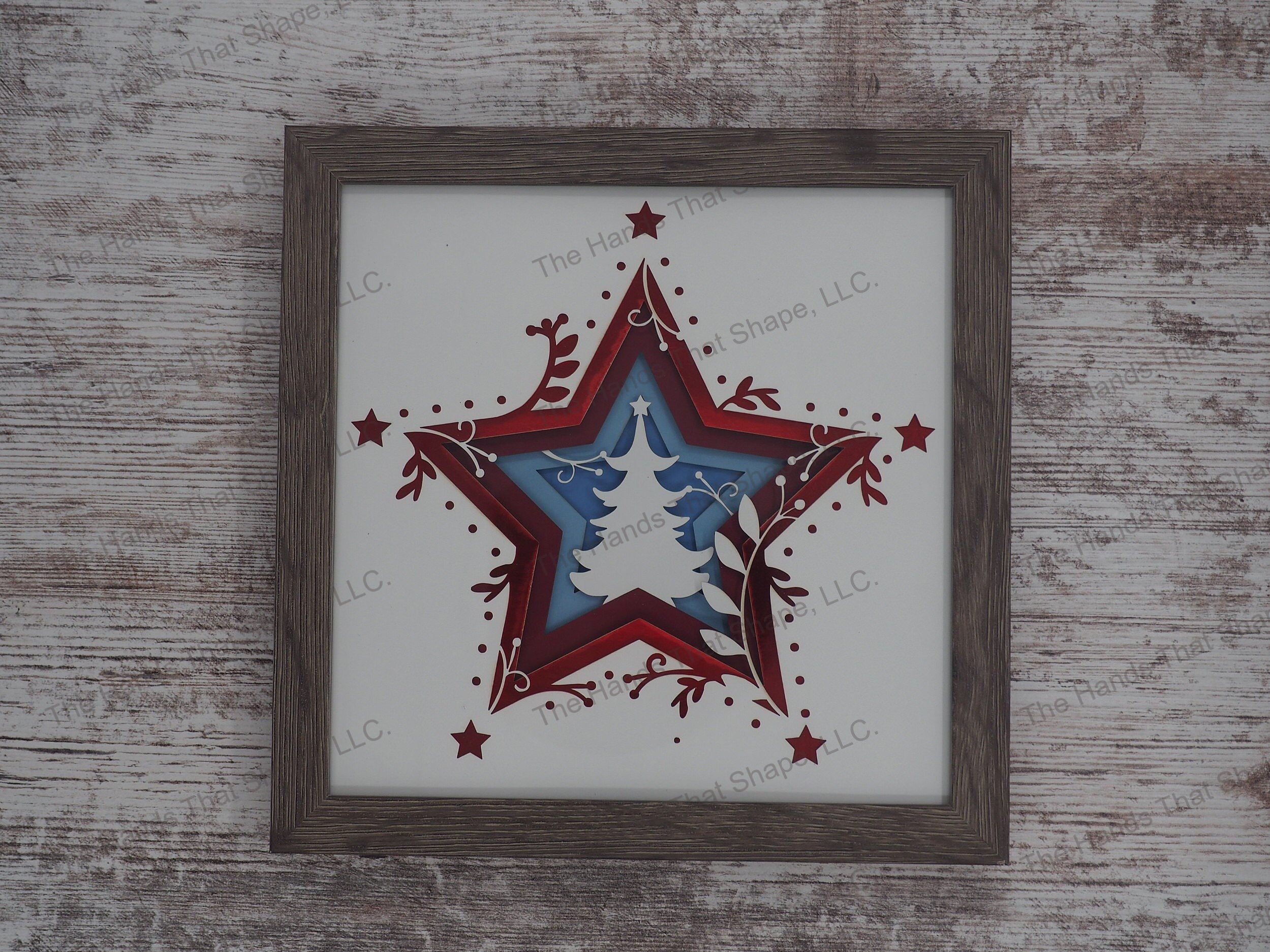 The shadow box features layers of cardstock paper to create a 3d Christmas Tree in the center of a multi-layer stacked star.
