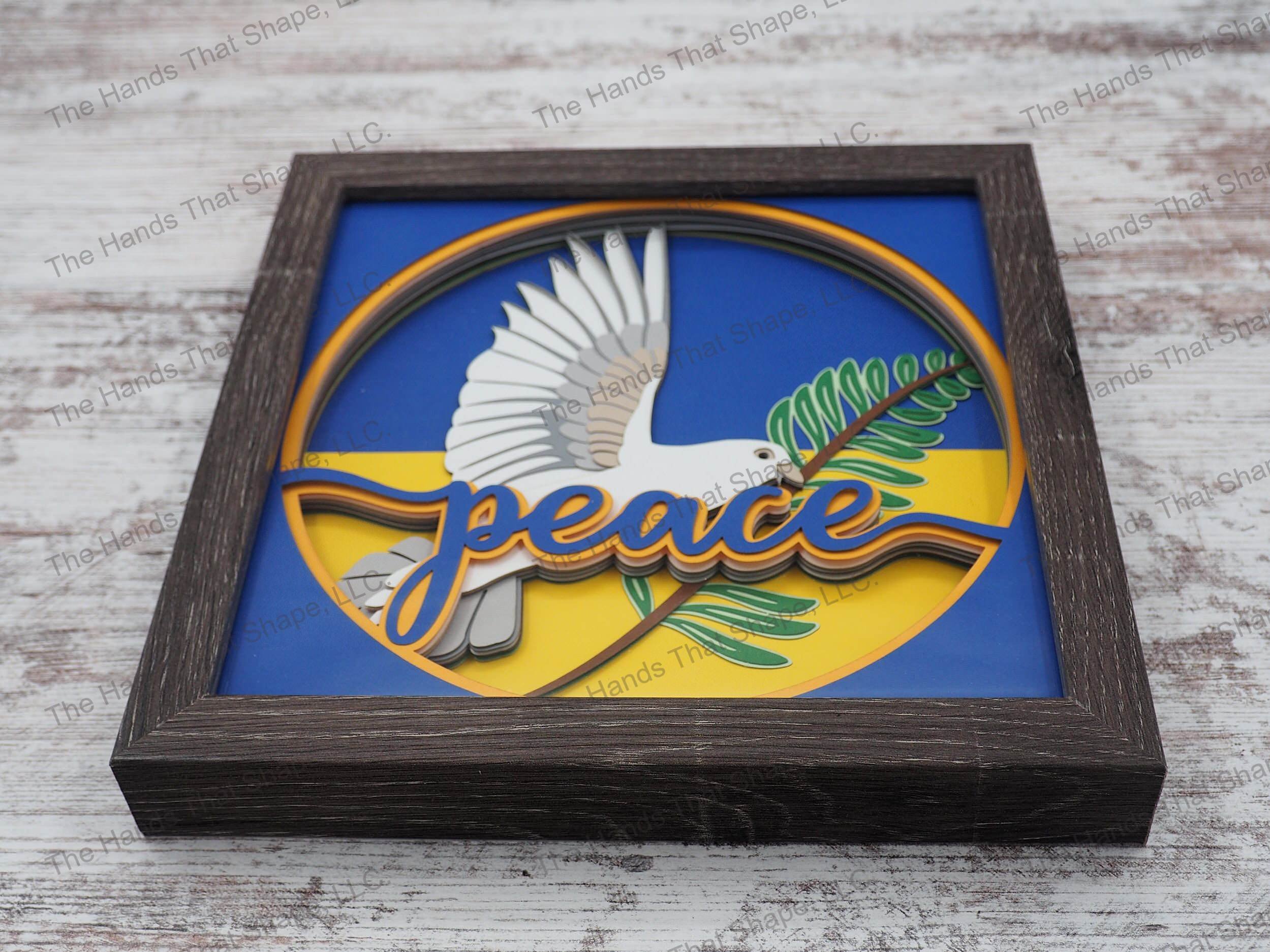 The “Peace” shadow box features a dove holding an olive branch as a reminder to add more tranquility to our lives. This one is made with Ukrainian flag colors.