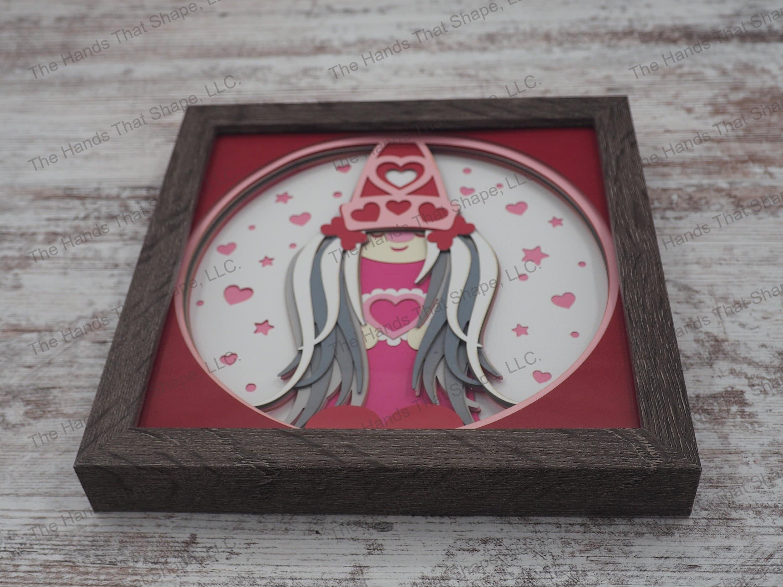 The ”Valentine Gnome” shadow box features a gnome covered in hearts and an abundance of reds and pinks, the colors of love.