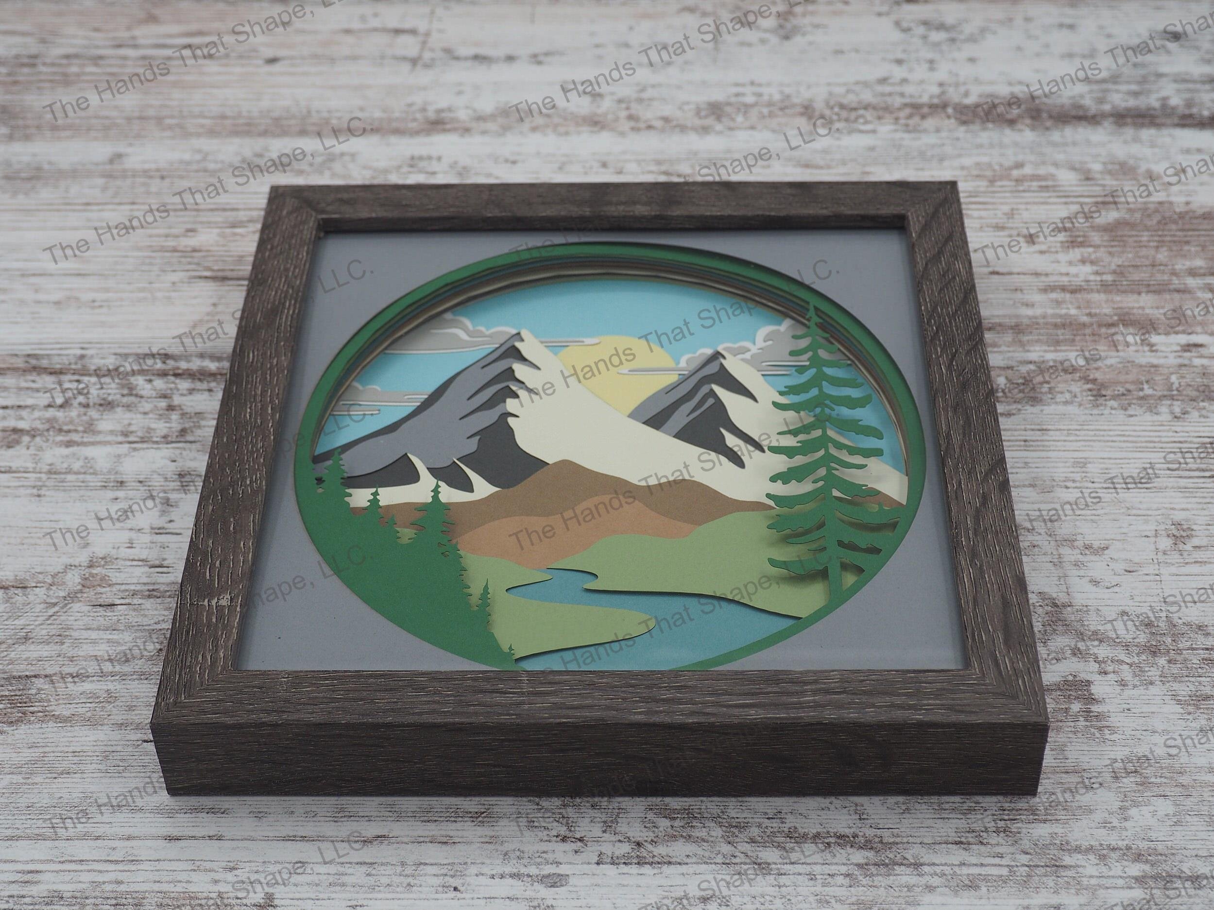 The “Red Mountain” shadowbox features mountains towering over rolling hills and a river. This shadowbox variation contains a natural/neutral palette.