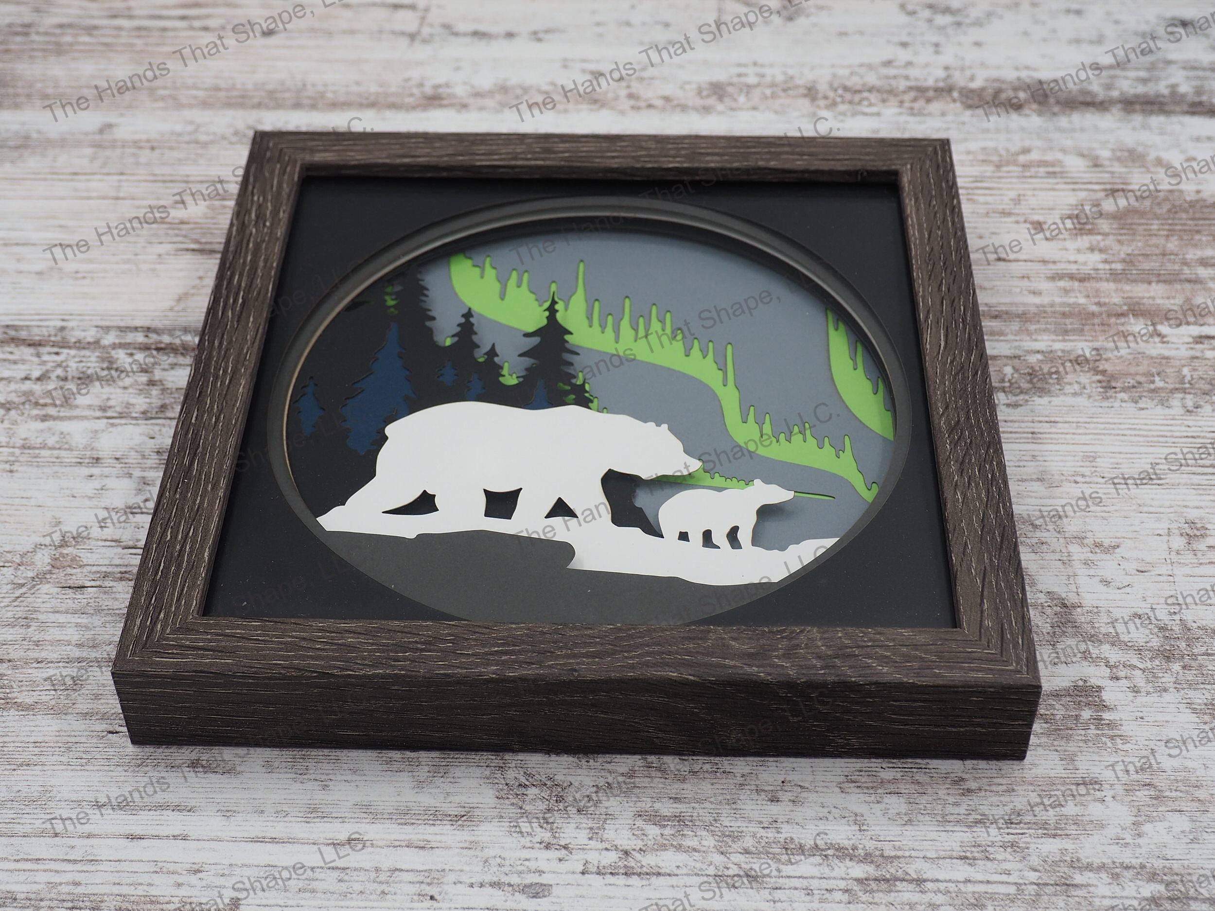 The shadow box features layers of cardstock paper to create a 3d picture of a mama bear and cub gazing at the mesmerizing northern lights.