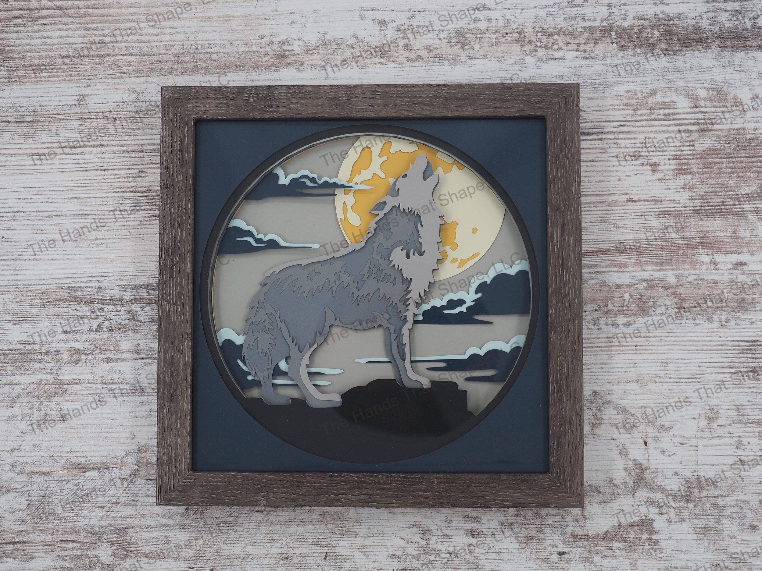 The “Howling Wolf” shadowbox features layers of cardstock paper to create a 3d picture of a lone wolf howling against the background of a full moon.