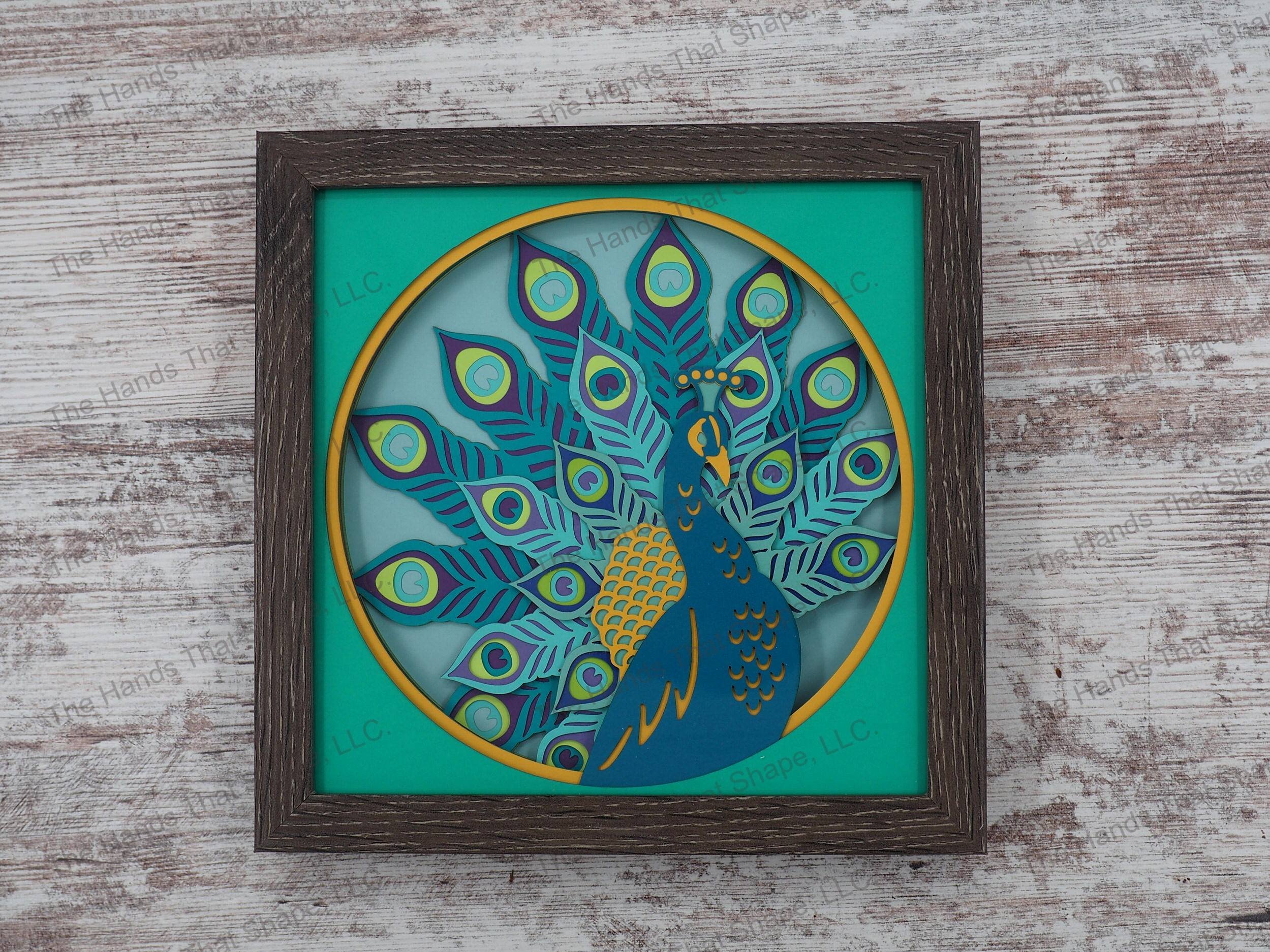 The “Peacock” shadowbox features layers of cardstock paper to create a 3d picture of a peacock, and it's magnificent feathers on full display.