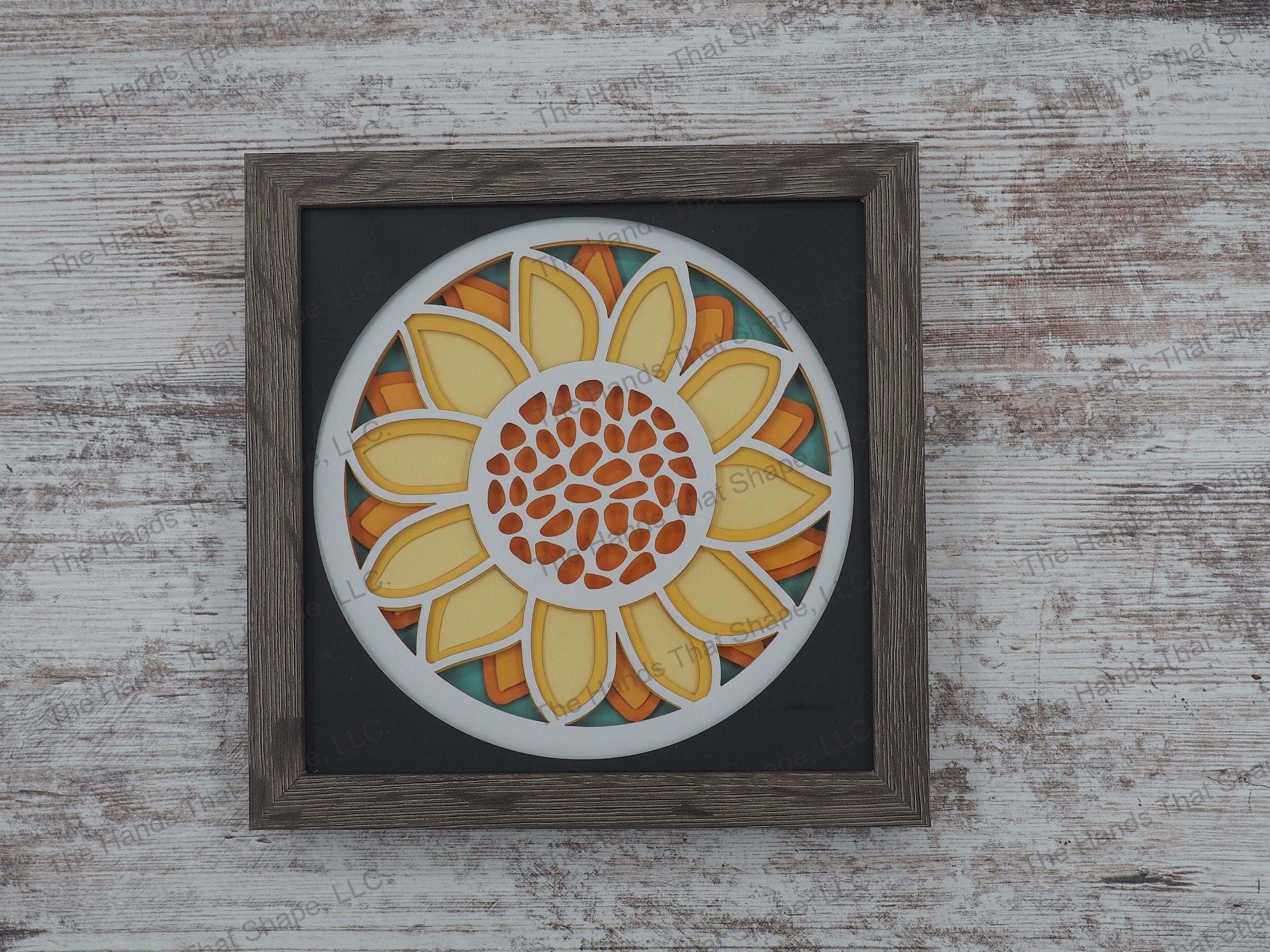 The shadow box features layers of cardstock paper to create a 3d picture of a large vibrant yellow sunflower.