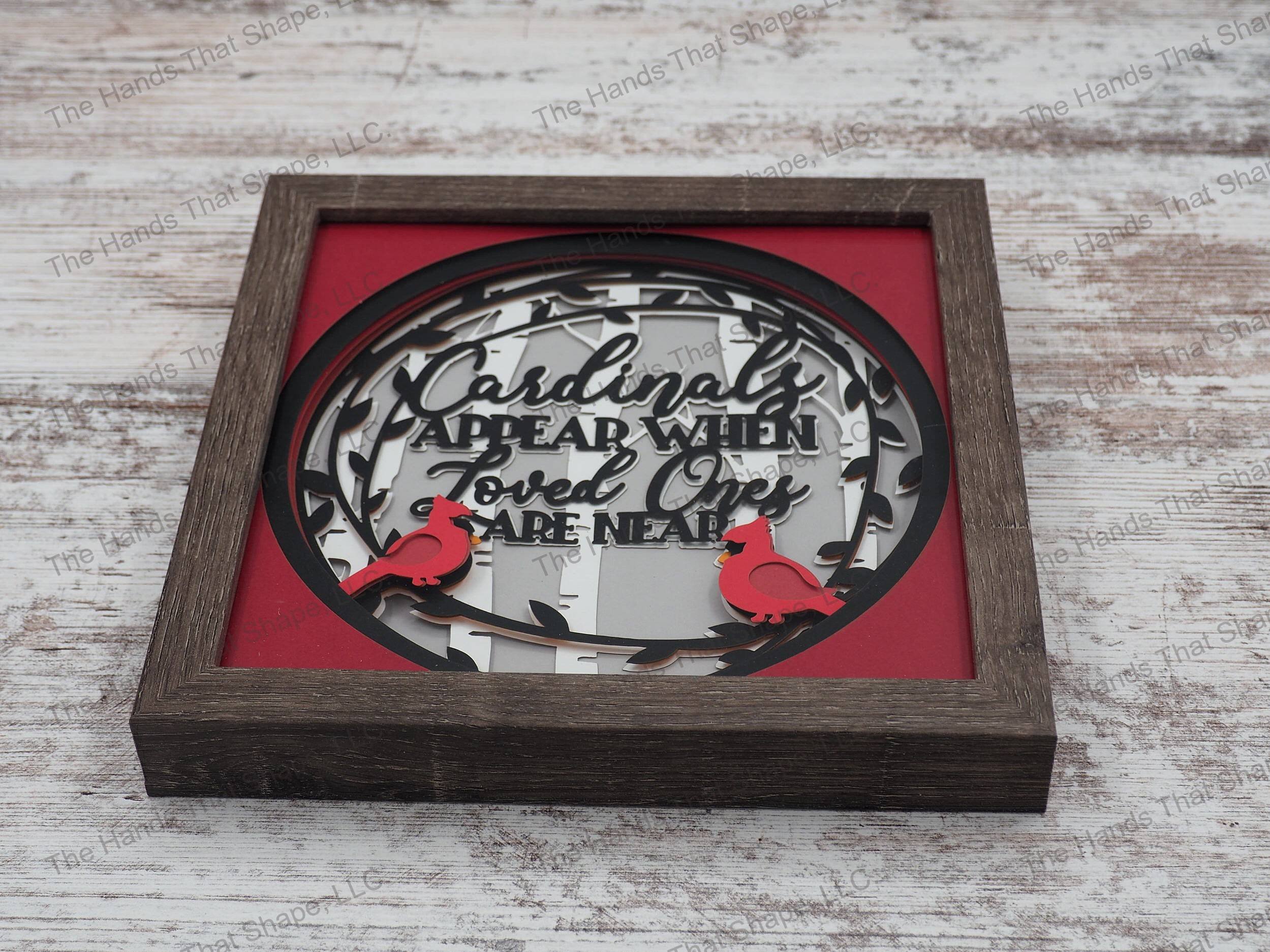 The shadow box features the phrase “Cardinals appear when loved ones are near” and features two red cardinals sitting on a black leaf wreath in a birch forest.