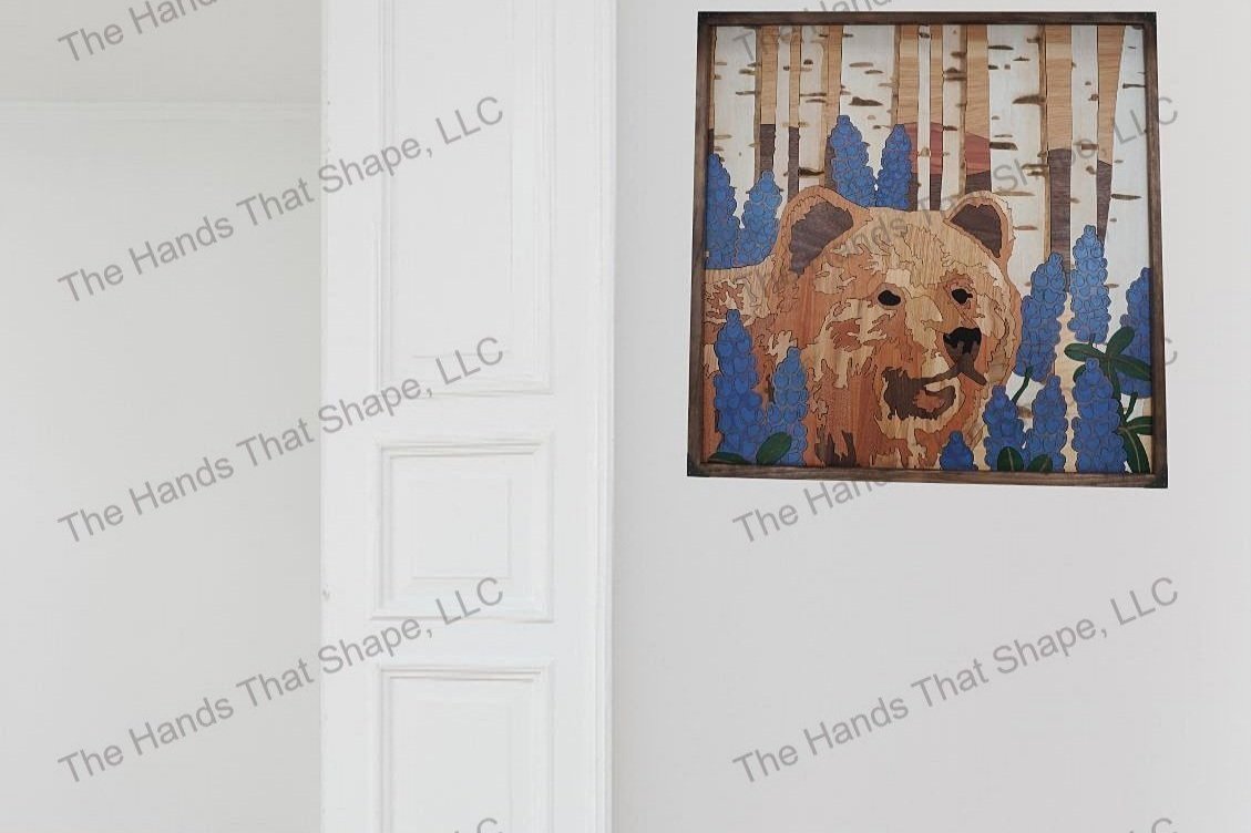 Finished bear and lupines wood wall art piece staged on a living room or bedroom wall next to a doorway.