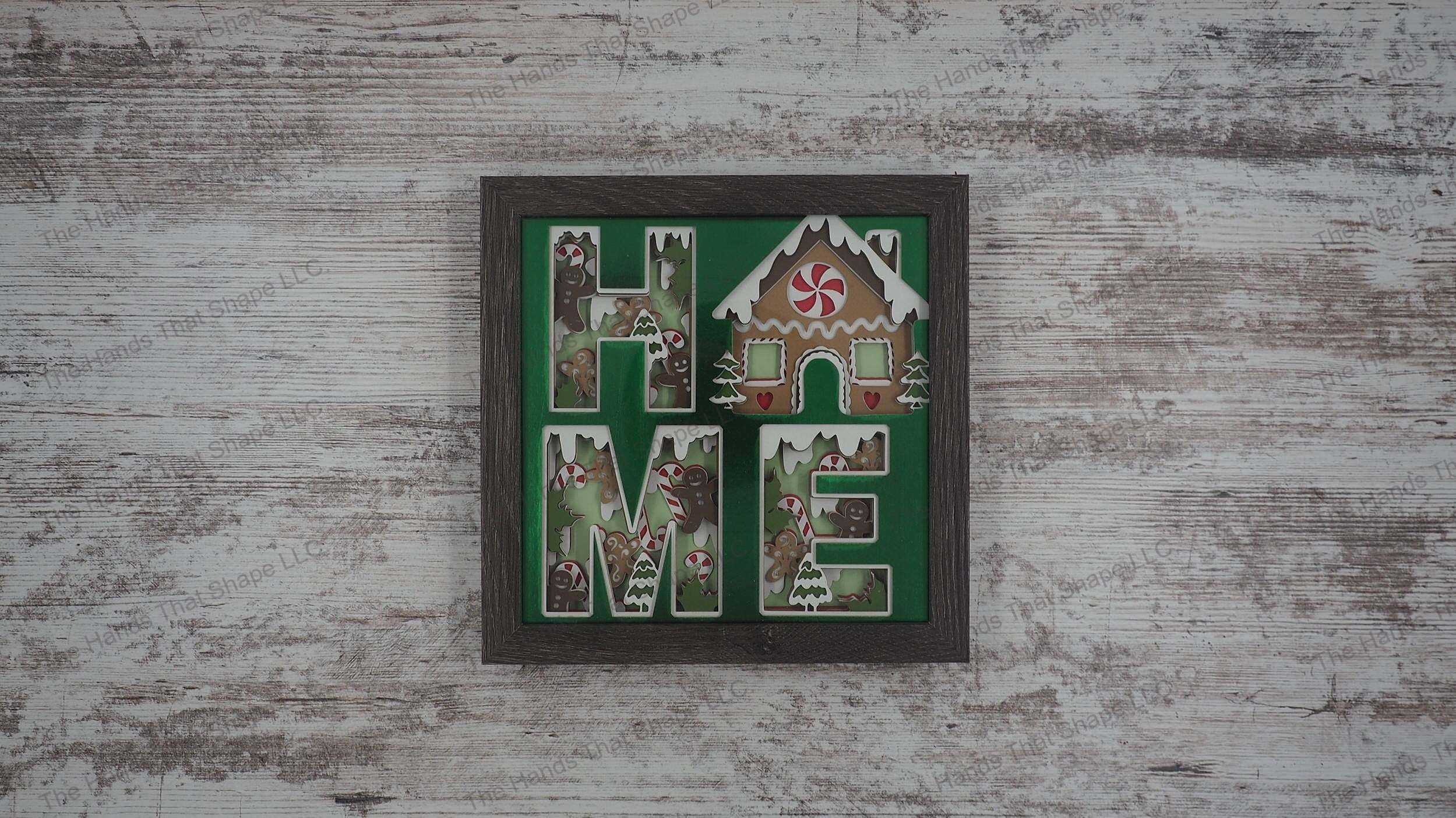 The shadow box features the word "HOME" cutout and filled-in with holiday themed cookies and candy canes. The "O" was replaced with a very festive Gingerbread House.