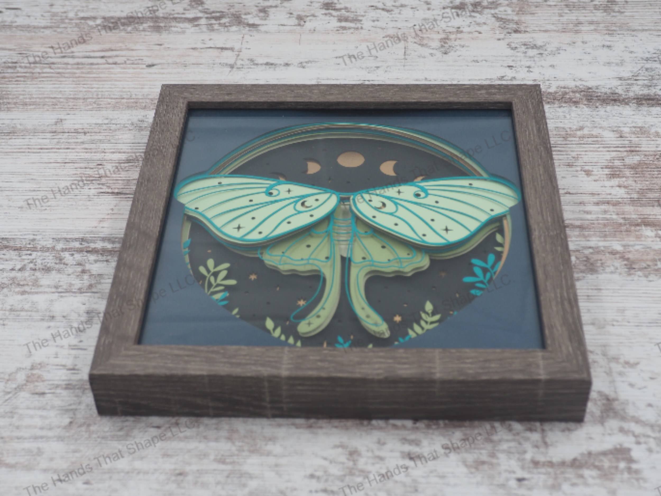 Luna Moth layered paper shadowbox with starry backdrop, moon phases, and greenery in 9-layer cardstock, encased in a glass-covered gray MDF frame.