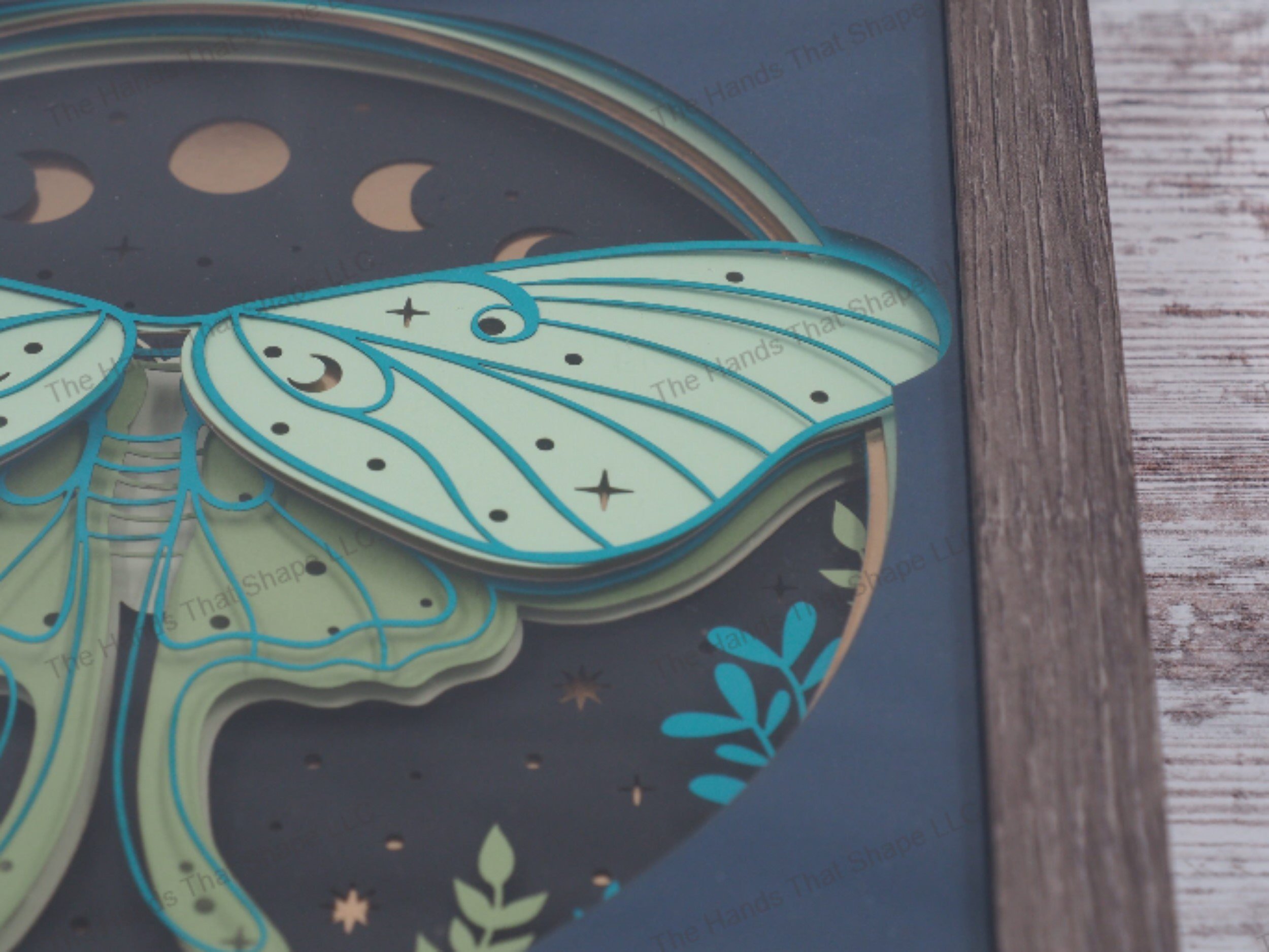 Luna Moth layered paper shadowbox with starry backdrop, moon phases, and greenery in 9-layer cardstock, encased in a glass-covered gray MDF frame.