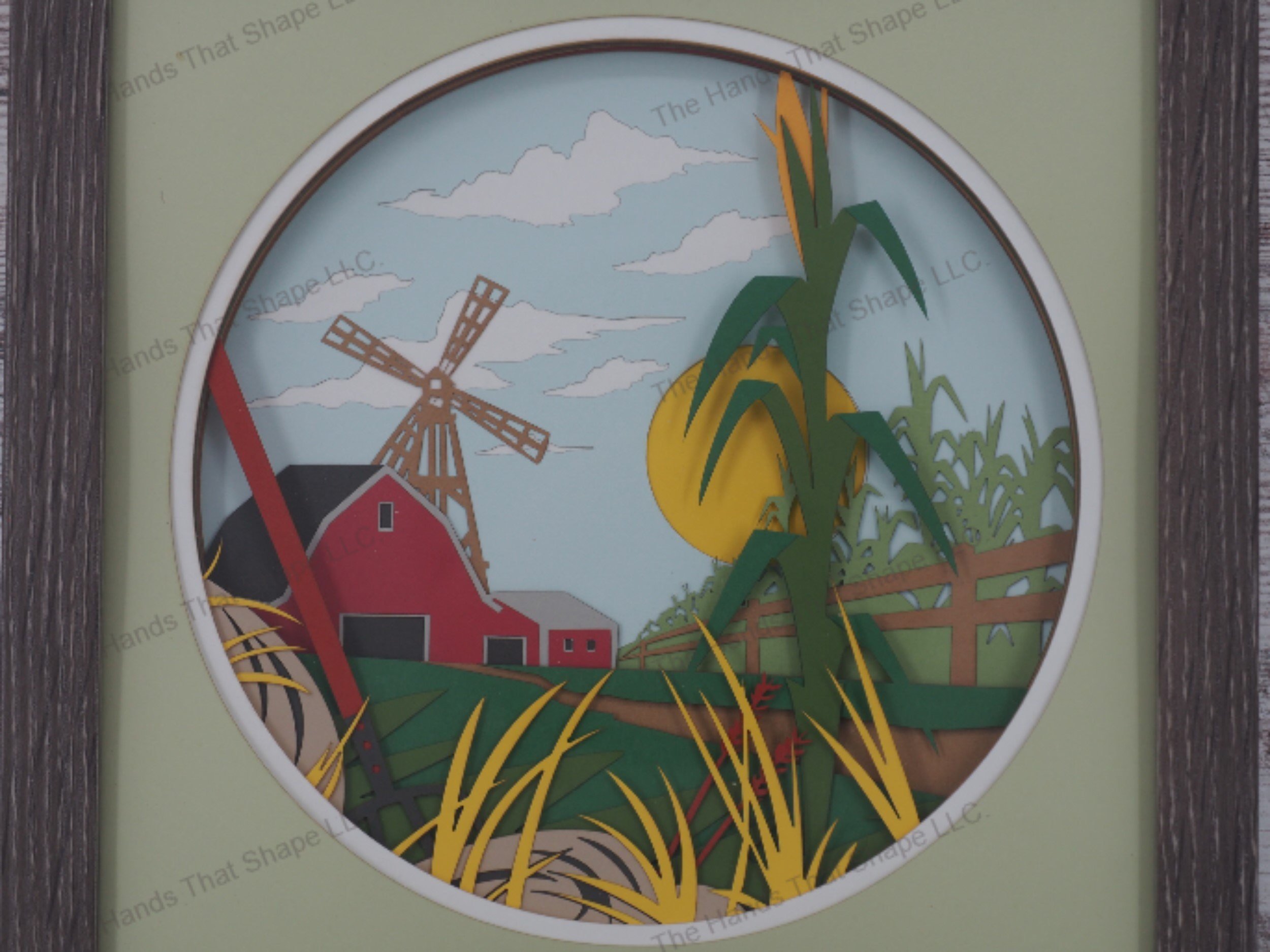 'Farm' layered paper shadowbox with a barn, windmill, cornfield, pitchfork, and sunny sky in 18-layer cardstock, framed in glass-covered gray MDF.