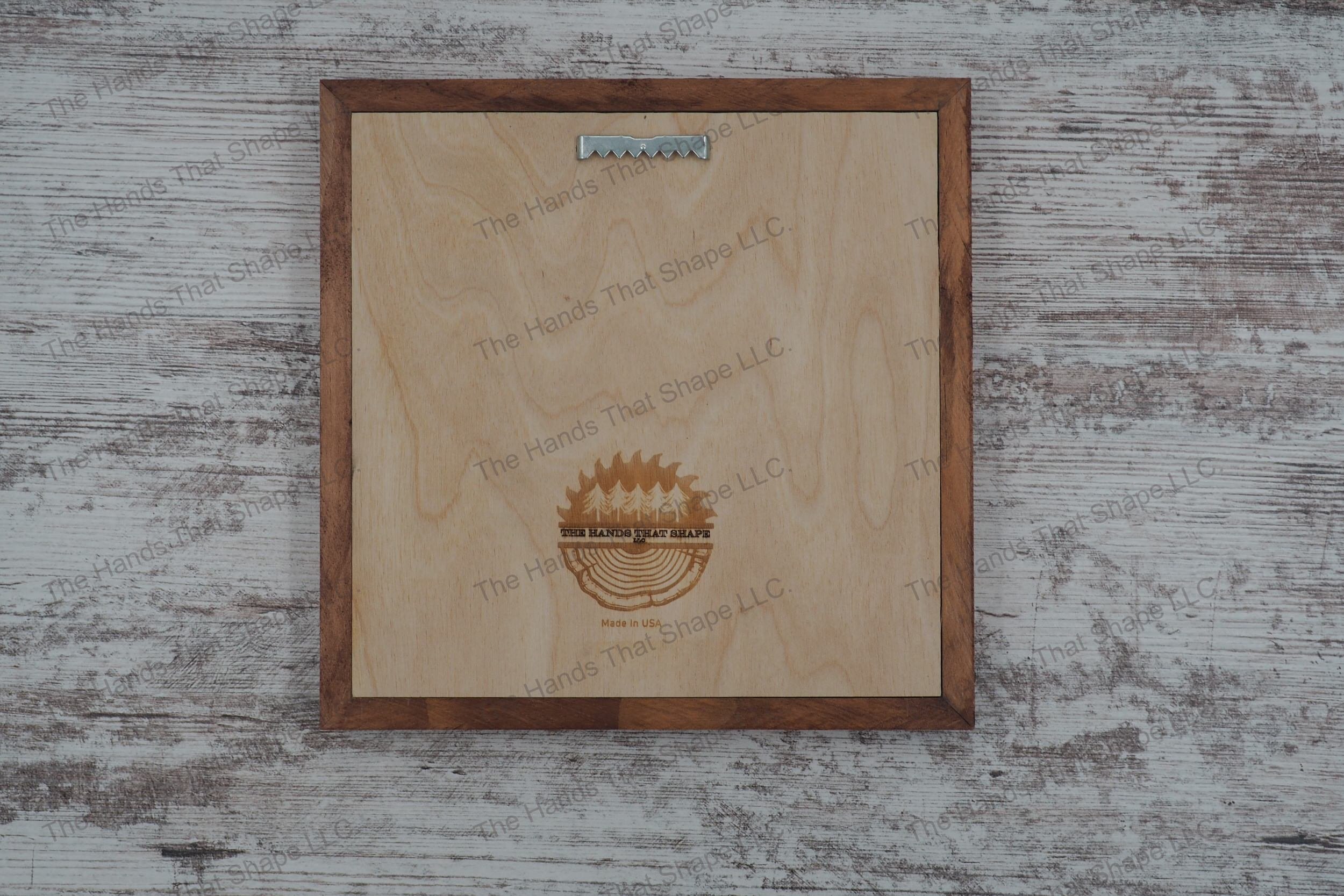 Example of the back side of the art showing The Hands That Shape, LLC logo and mounted sawtooth hanger