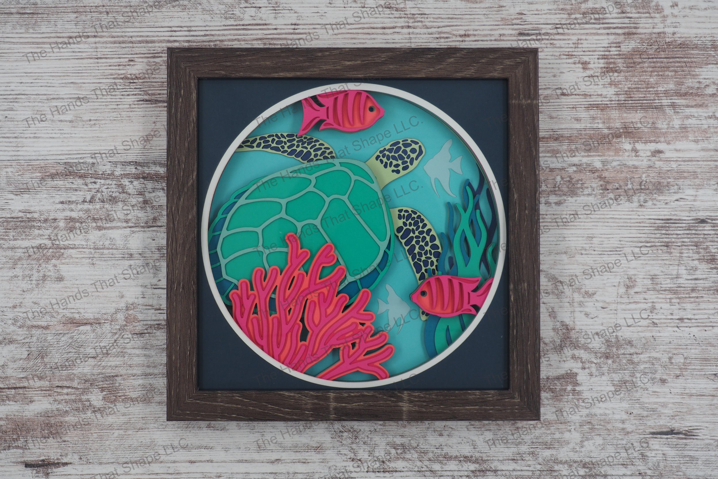 A layered paper shadowbox depicting an underwater scene with a sea turtle, tropical fish, and coral, crafted from 12 layers of cardstock in a gray MDF frame.