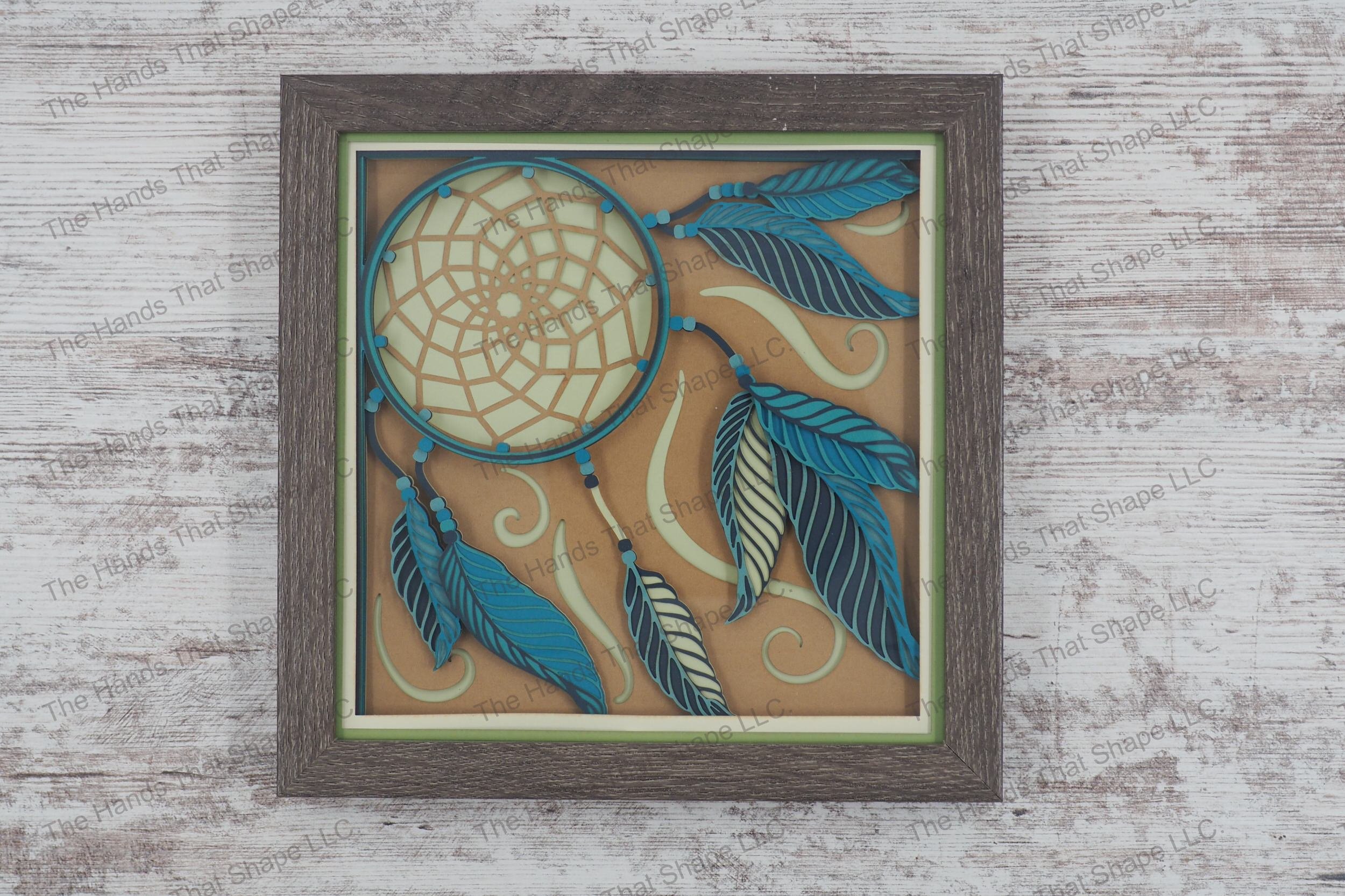 Dream Catcher layered paper shadowbox features a dream catcher, feather sets, and beaded cords on a swirled background, in 10-layer cardstock and gray frame.