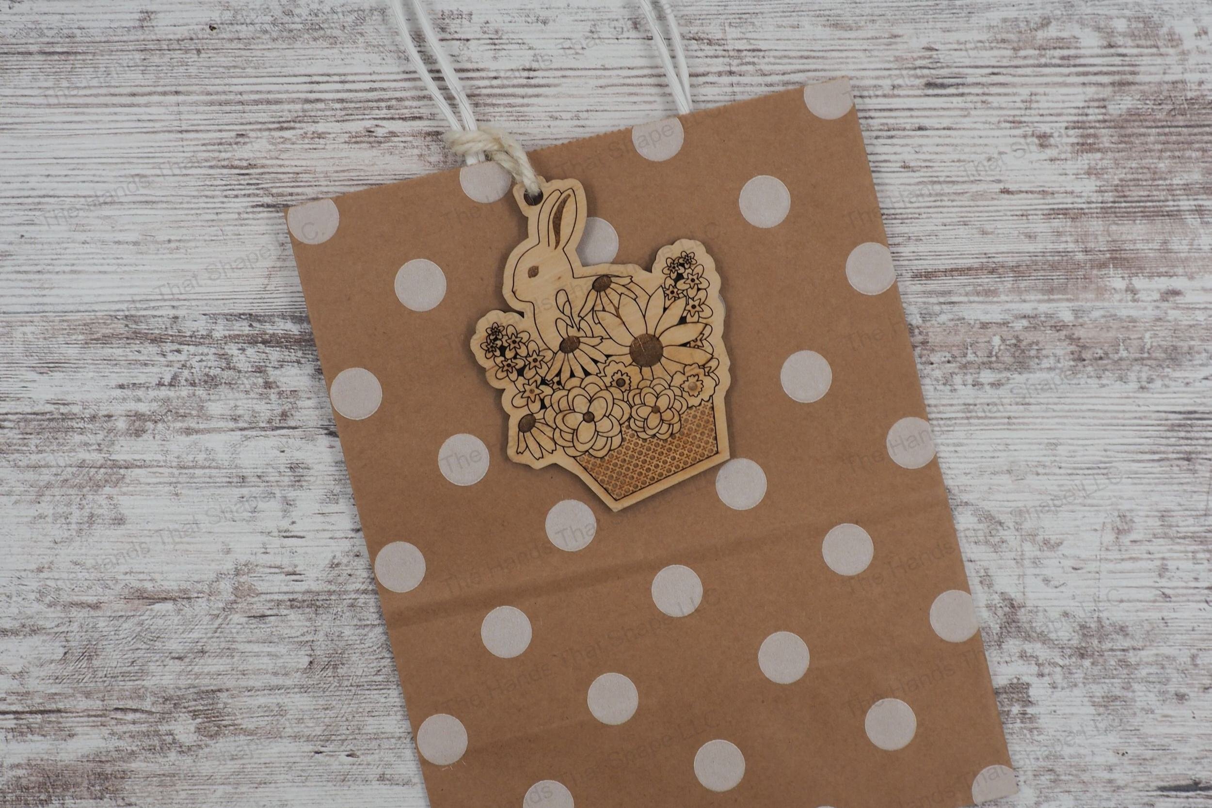Craft charming ornaments with our laser-ready file featuring a bunny in a basket surrounded by flowers, offering two designs for customization with names.