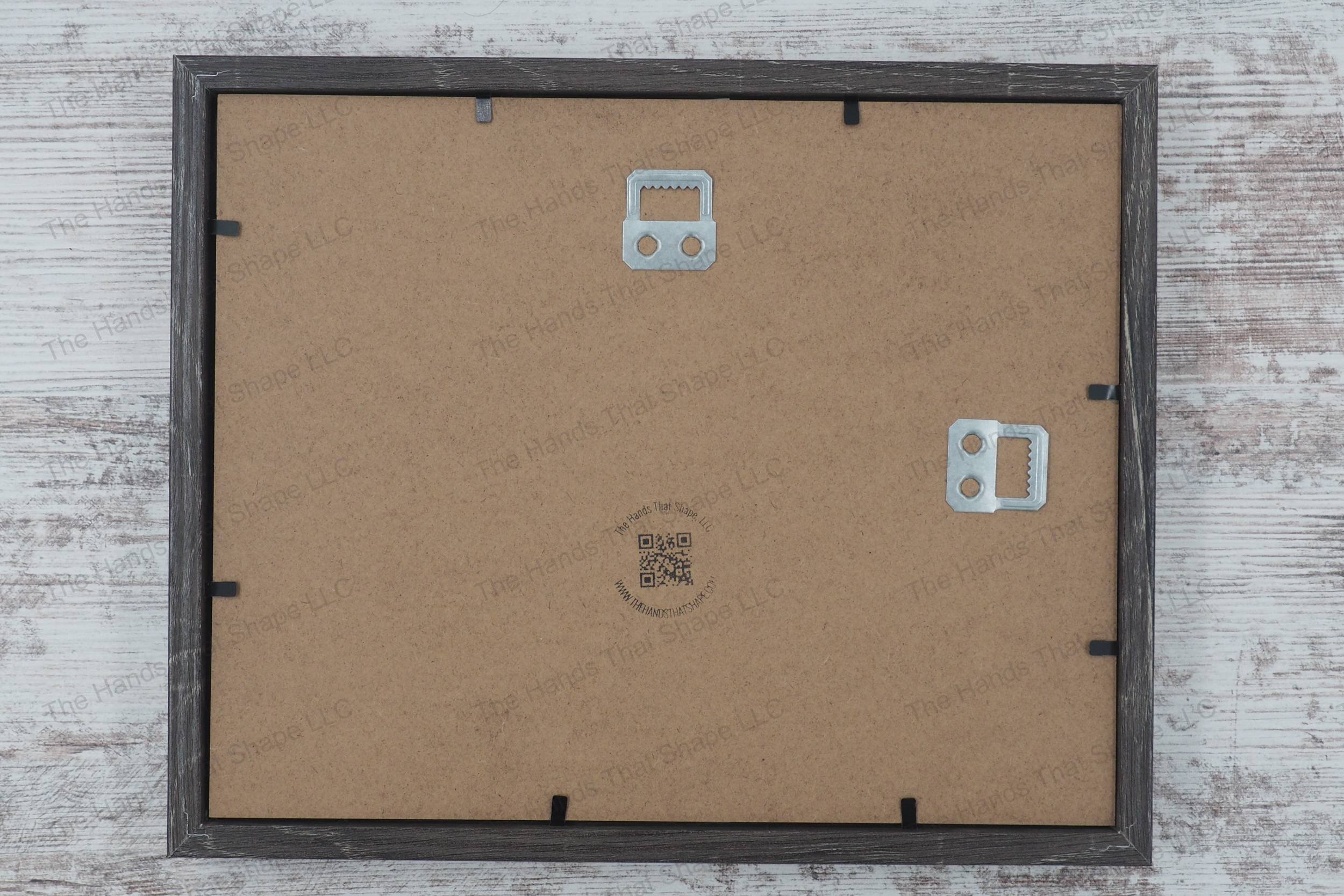 The back side of the layered cardstock paper shadow box that uses sheets of paper to create a 3d image. The backside shows The Hands That Shape, LLC logo and mounted hanger.