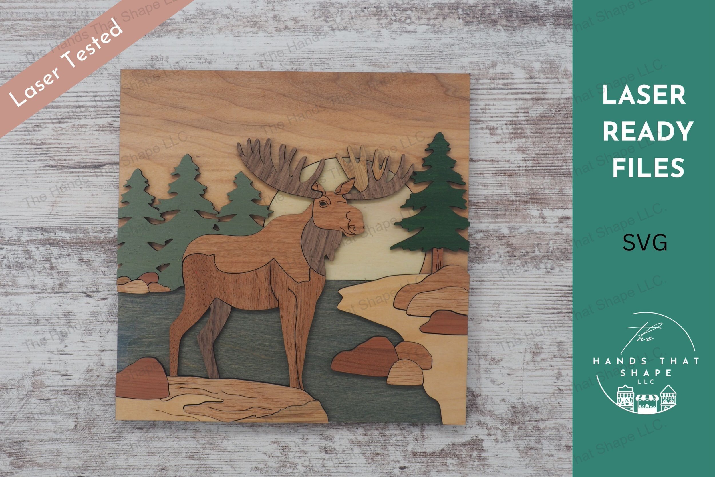 Craft a stunning 3D inlay art piece with our laser-ready file featuring a majestic moose next to a stream, with a backdrop of pine trees and a setting sun.