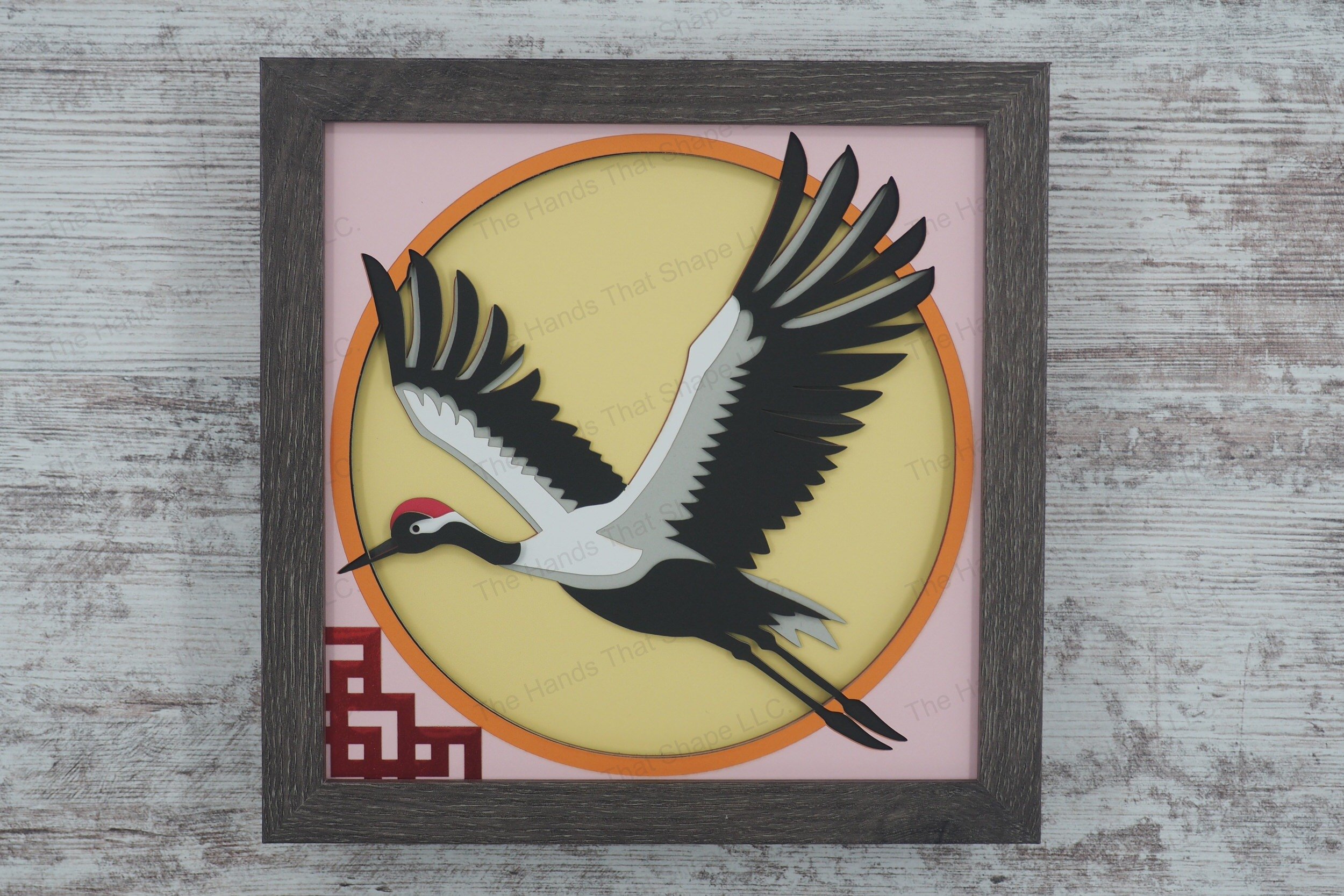 A serene 3D paper shadowbox featuring a Japanese red crown crane in flight above a lattice design, crafted from layers of cardstock for elegant depth.