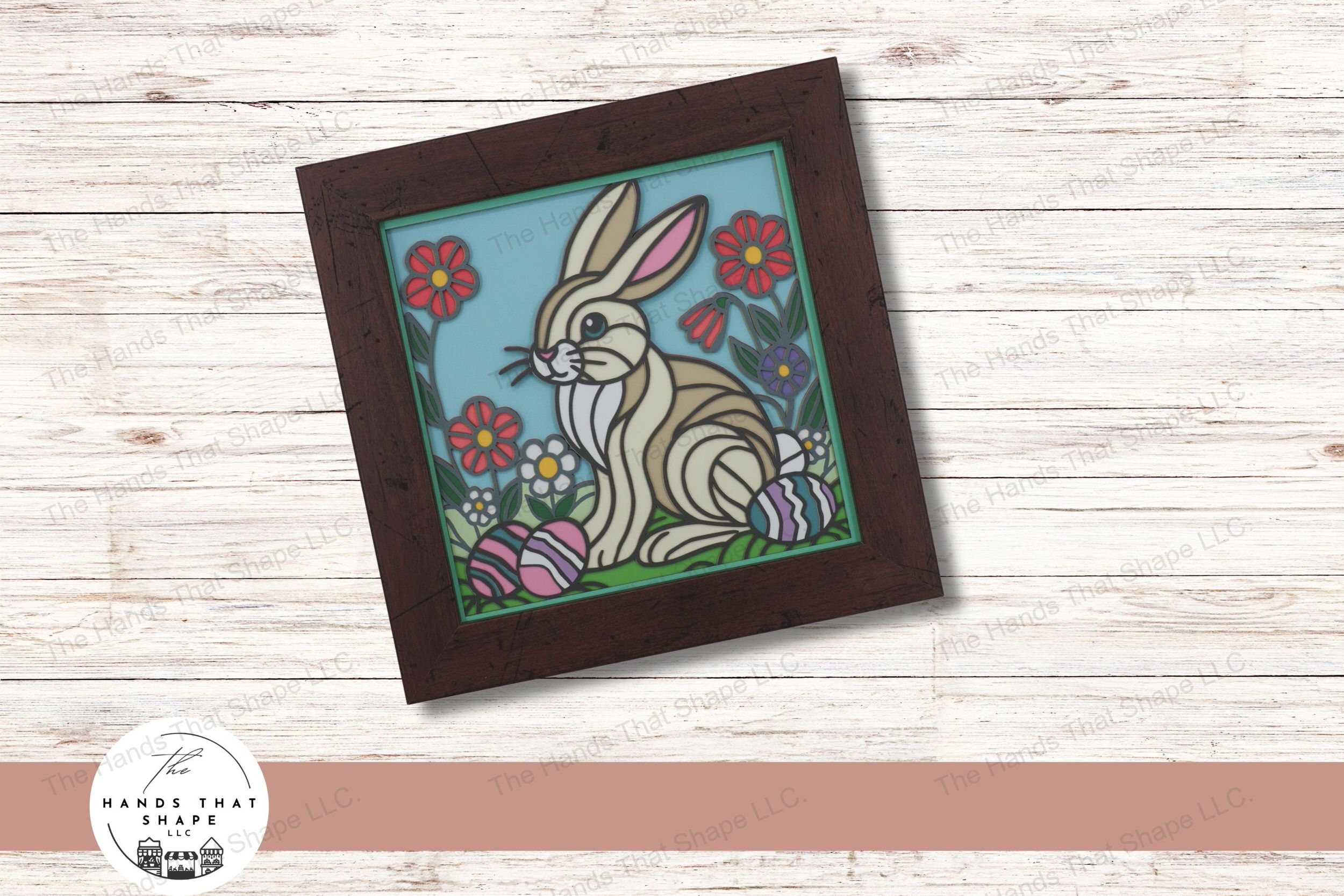 This layered cardstock art piece captures a charming Easter Bunny scene, featuring the bunny amidst colorful spring flowers and pastel eggs.