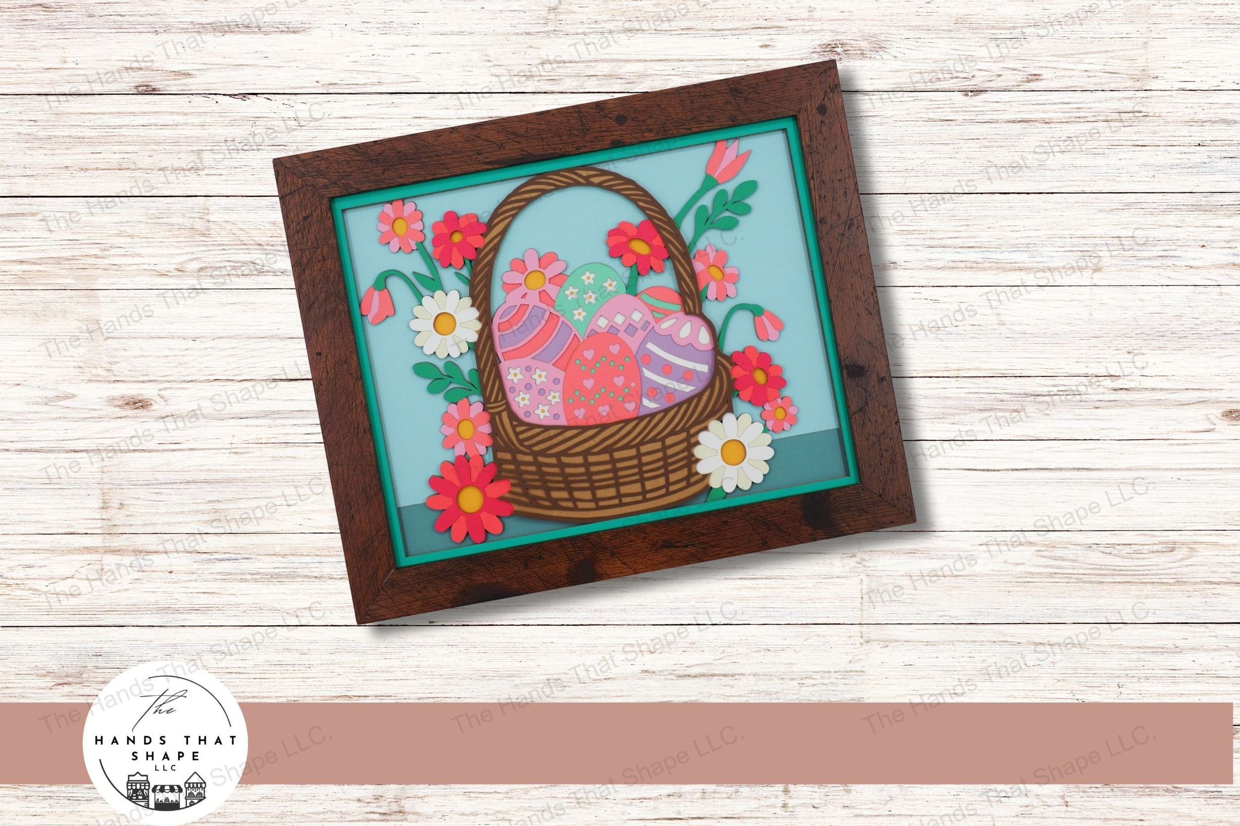 This layered cardstock art piece showcases a beautifully woven Easter basket filled with decorated eggs and surrounded by a burst of colorful spring flowers.