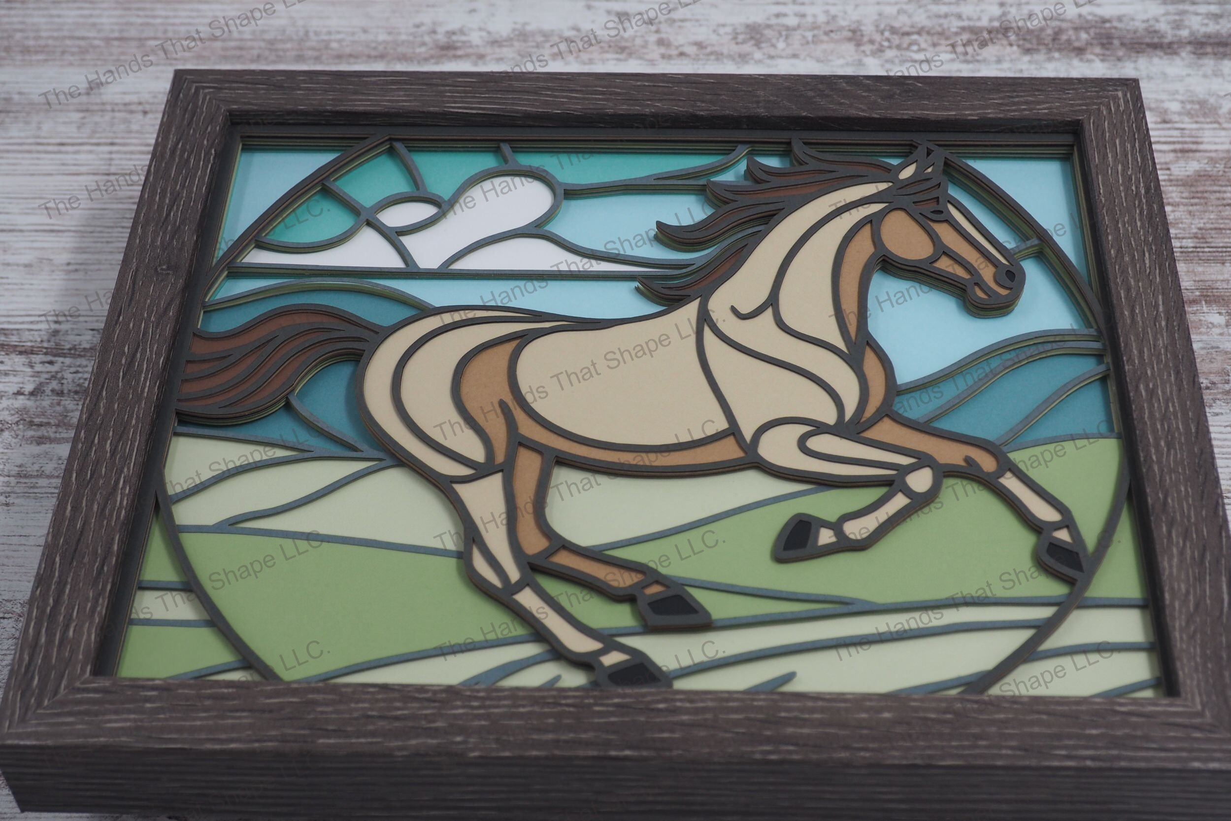Experience the dynamic beauty of a horse in motion with this framed layered paper shadowbox art, featuring a horse galloping through hilly grasslands.
