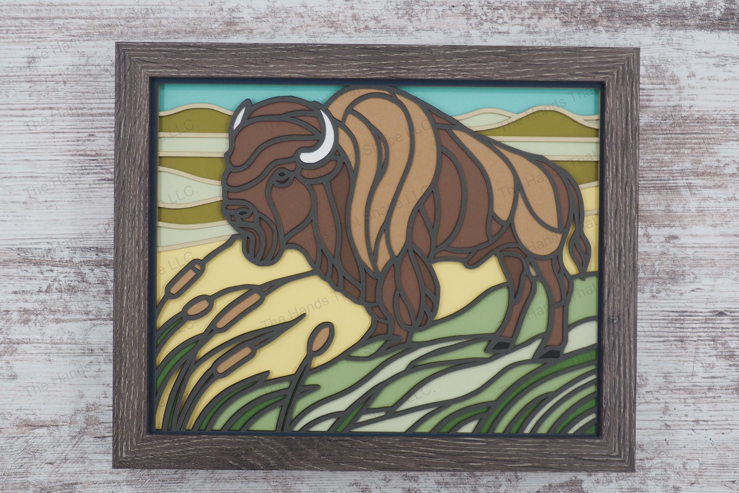 Discover the majestic presence of a bison depicted in stained glass style, standing on a prairie with rolling hills, encased in a glass-covered gray MDF frame.