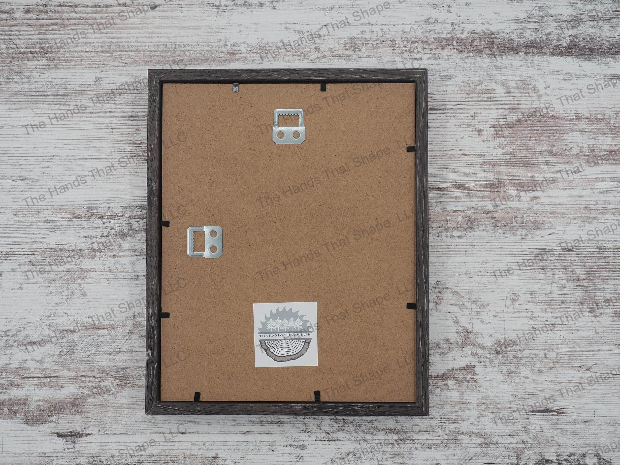 The back side of the layered cardstock paper shadow box that uses sheets of paper to create a 3d image. The backside shows The Hands That Shape, LLC logo and mounted hanger.
