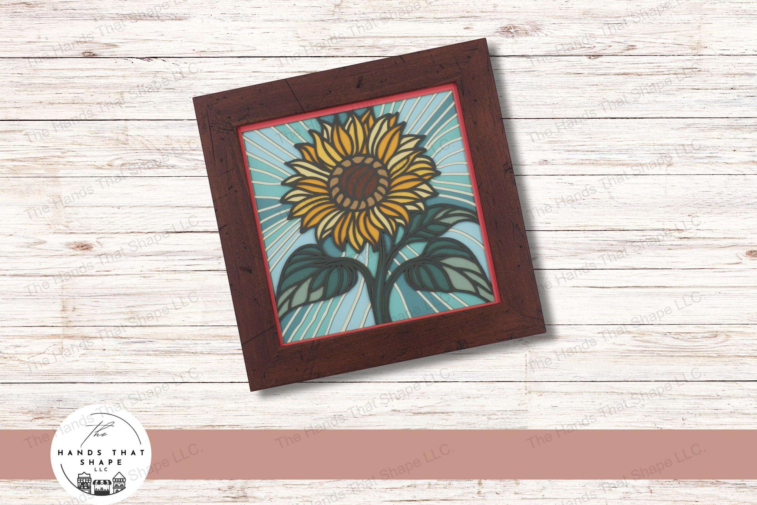 This layered cardstock art piece beautifully captures a vibrant sunflower, set against a striking blue background that radiates outward.