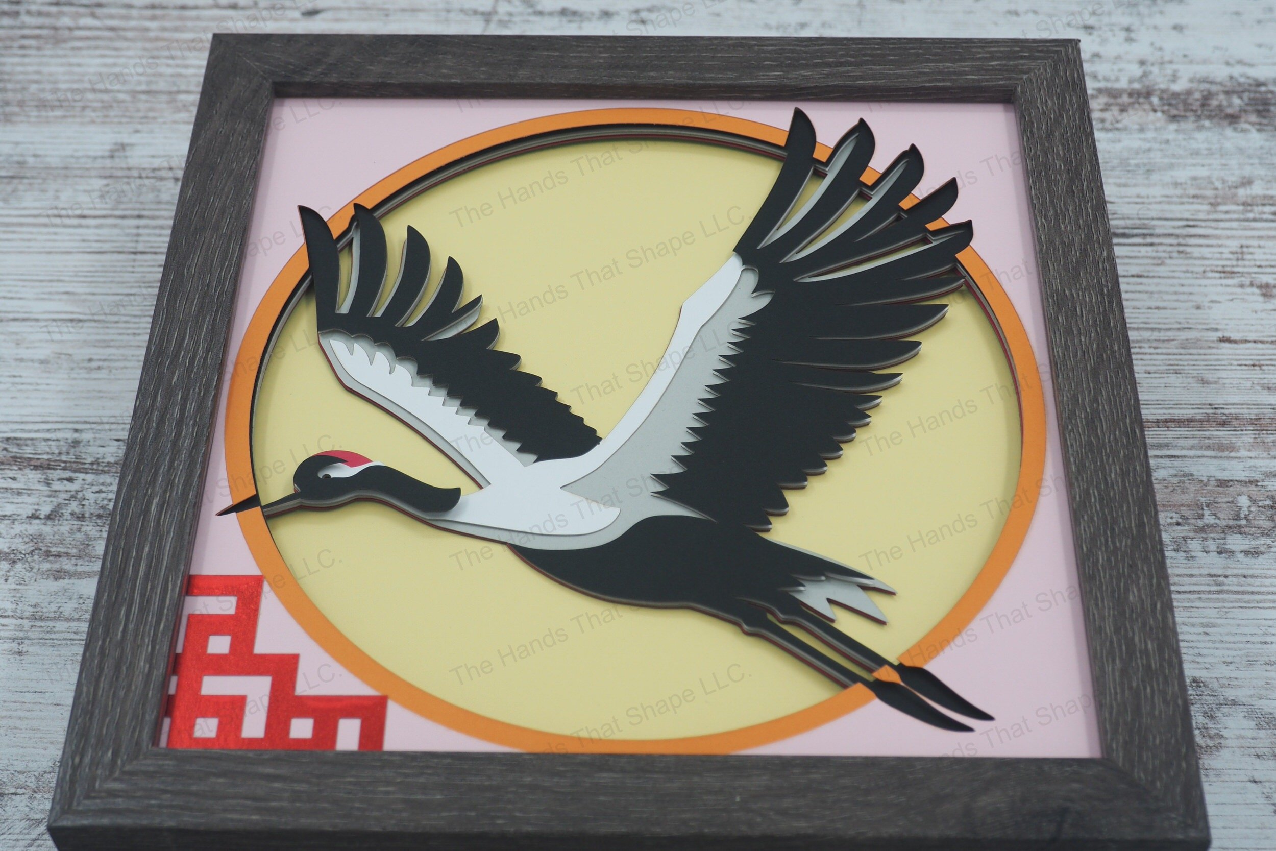 A serene 3D paper shadowbox featuring a Japanese red crown crane in flight above a lattice design, crafted from layers of cardstock for elegant depth.
