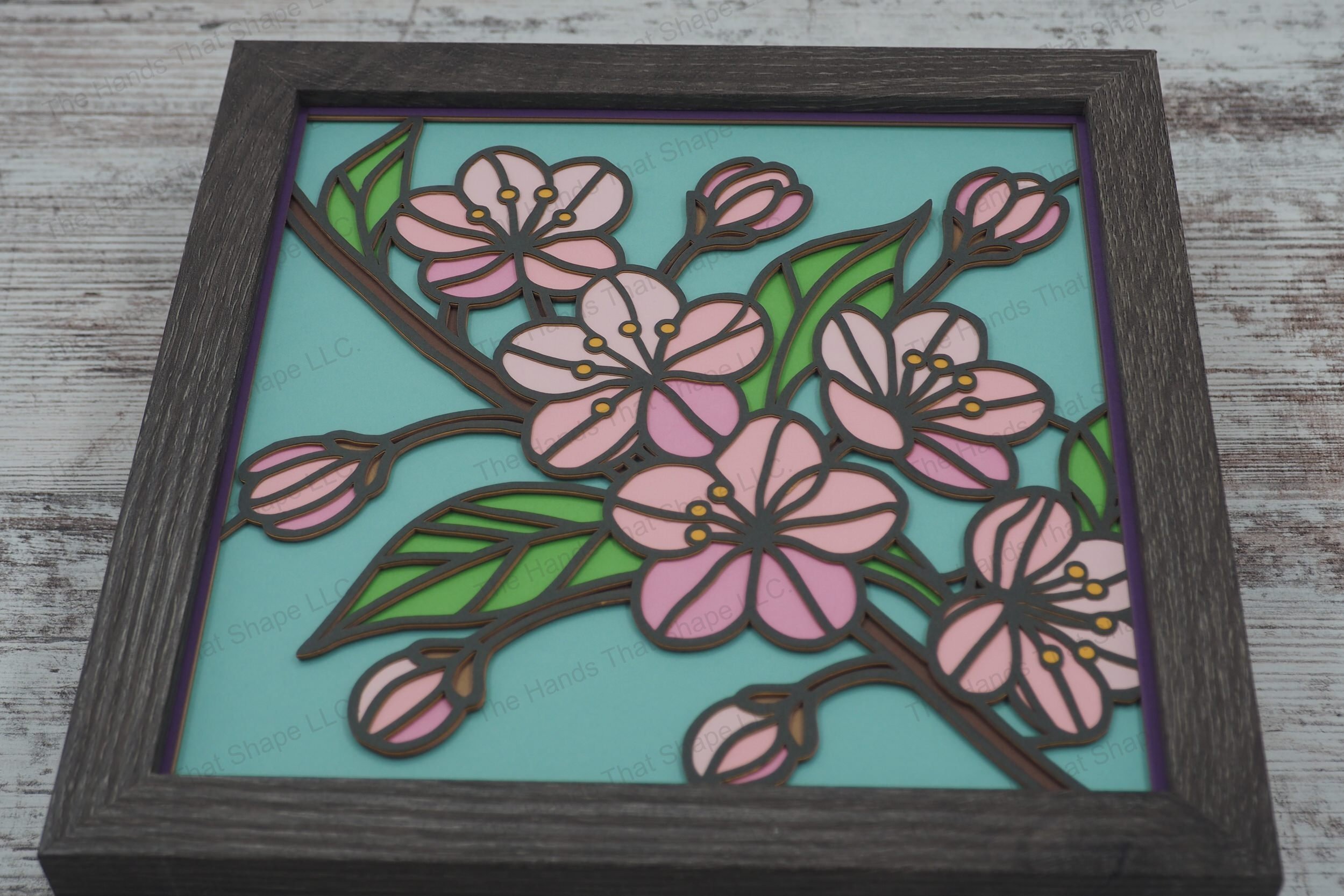 Experience the beauty of cherry blossoms through this intricately crafted shadowbox, featuring a branch in bloom styled in stained glass with colored cardstock.