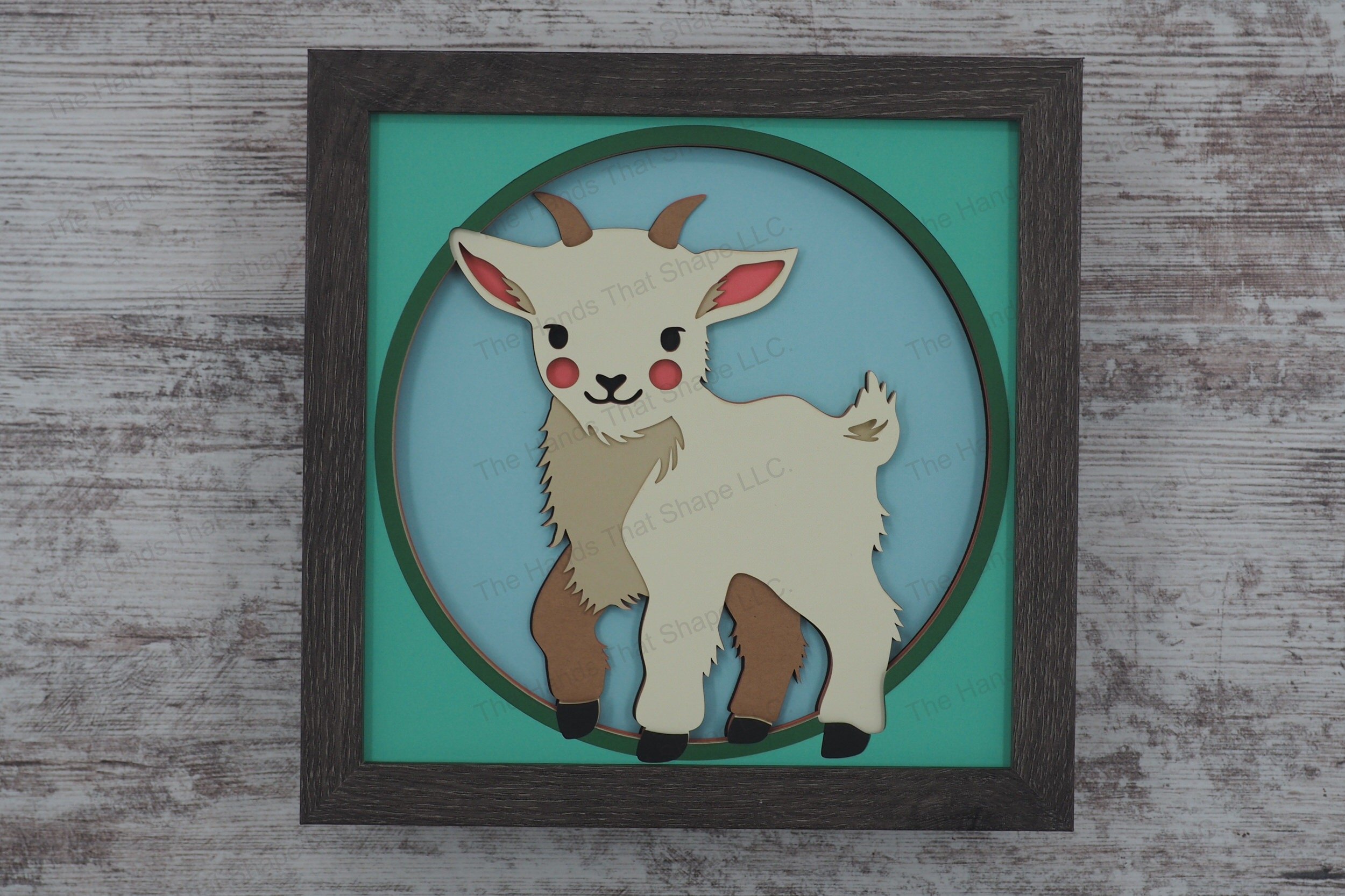 This layered paper art shadowbox captures the charm of a sweet baby goat, standing curiously and looking directly at the viewer in a whimsical 3D display