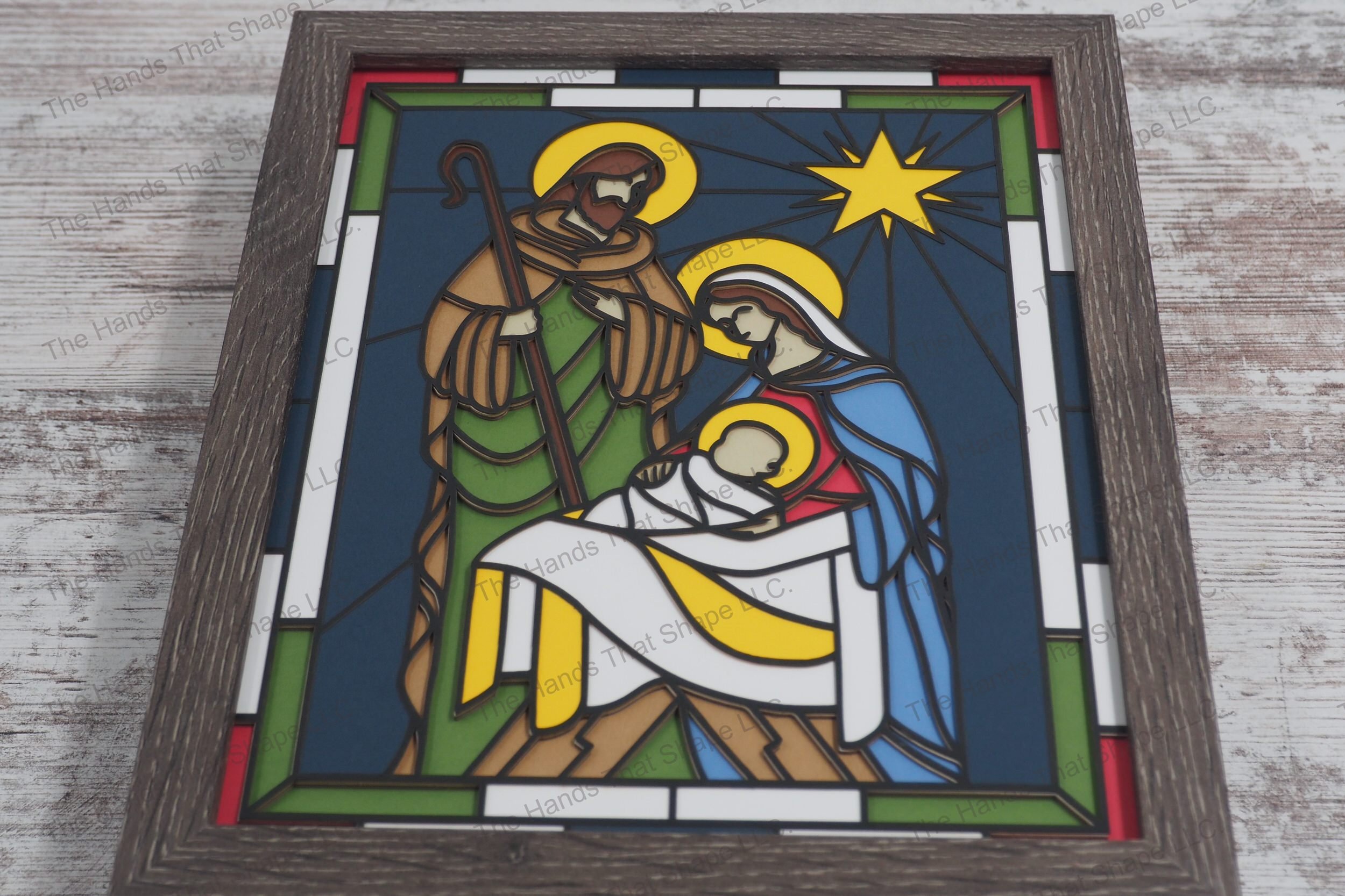 A stunning depiction of the Nativity scene crafted in a stained glass style using 10 layers of colored premium cardstock to create a vivid 3D effect.