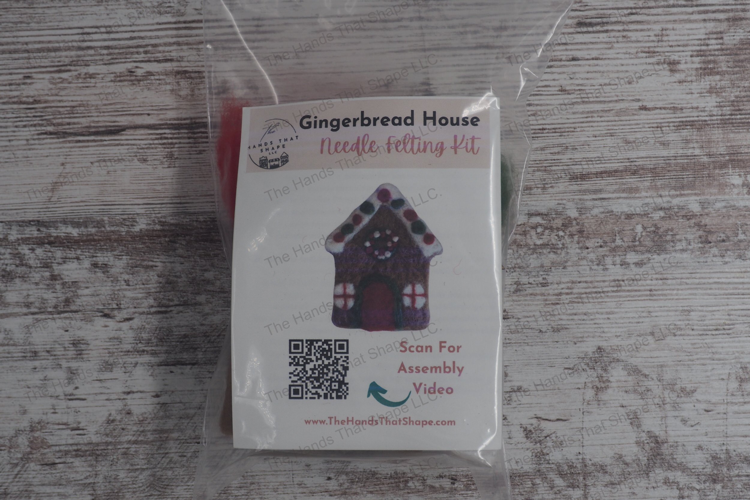 Craft a festive gingerbread house with this needle felting kit featuring colored wools, felting needles, a foam pad, and a wooden frame template.