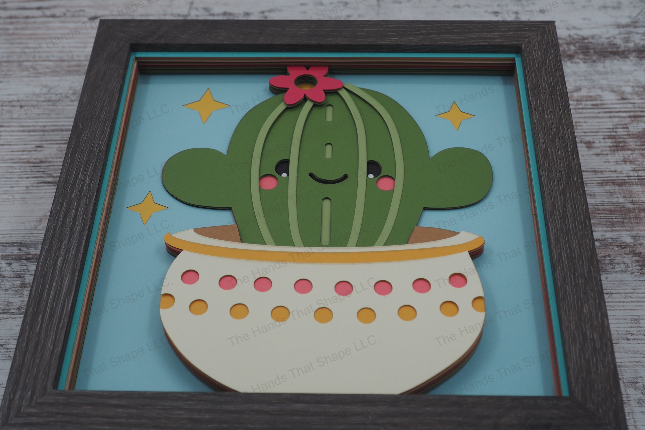 Delight in the whimsical charm of a smiling cactus with human-like features, crafted from layers of colored premium cardstock to create a vivid 3D effect.