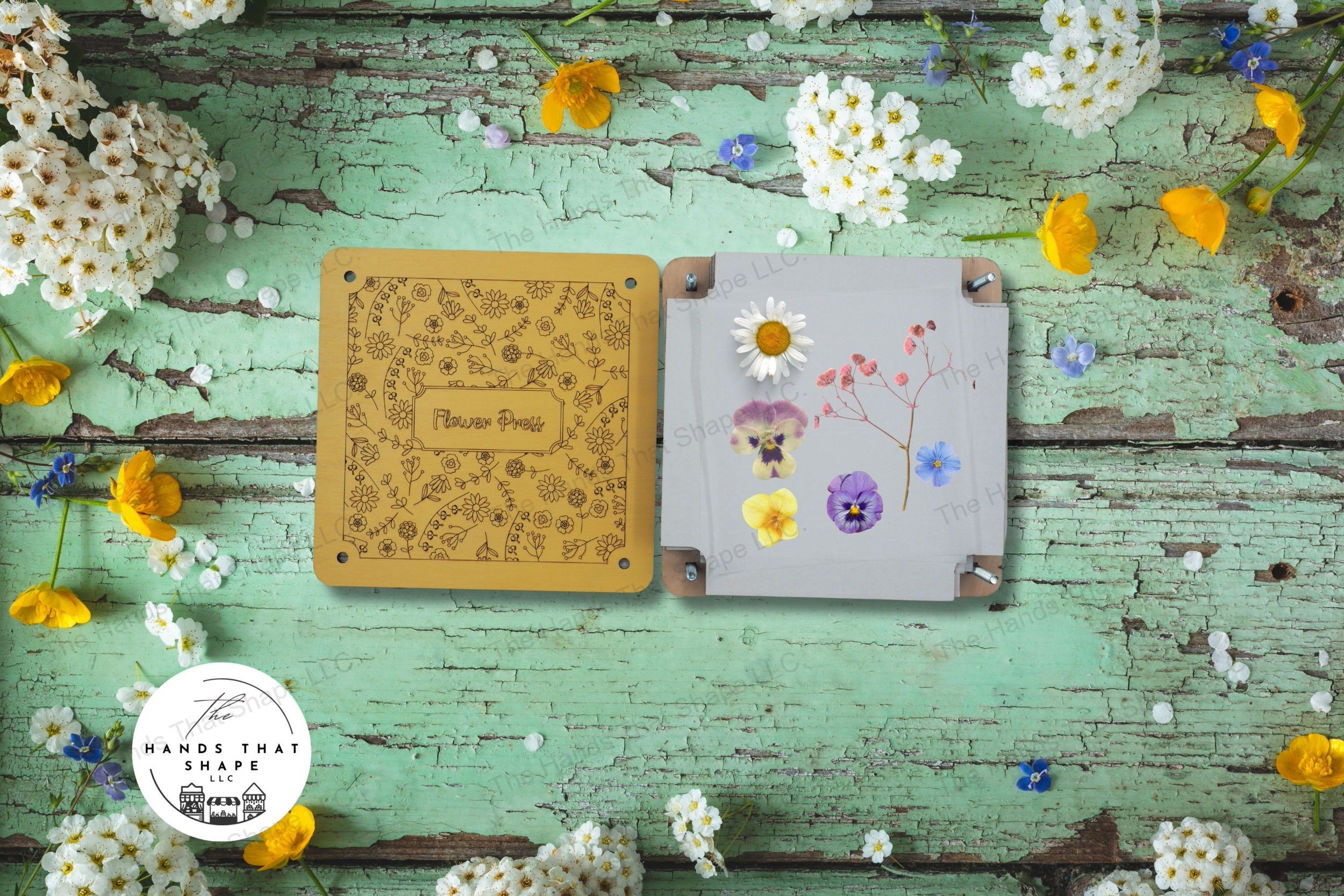 A decorative wooden flower press with laser-marked floral design, complete with cardboard and parchment layers for preserving blooms.