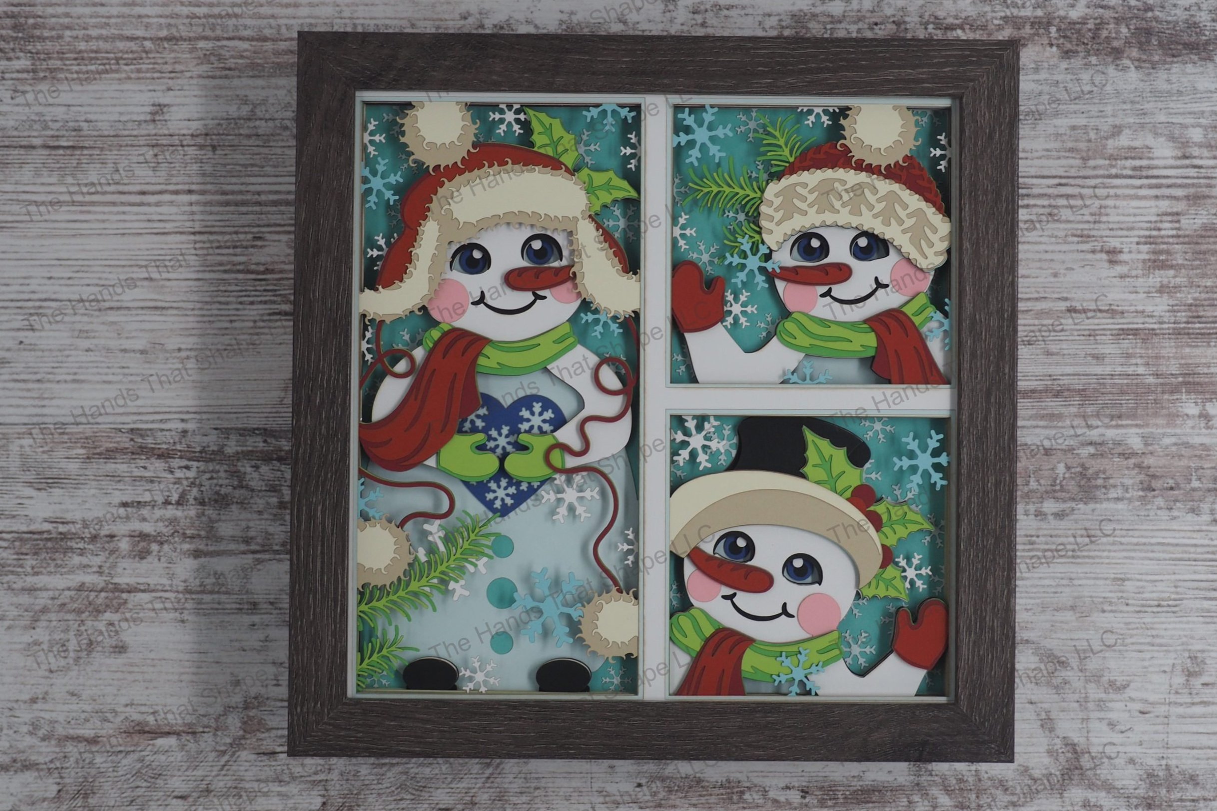 A captivating layered paper shadowbox featuring three distinct snowman scenes, each in its own window, with joyful expressions and festive accessories.