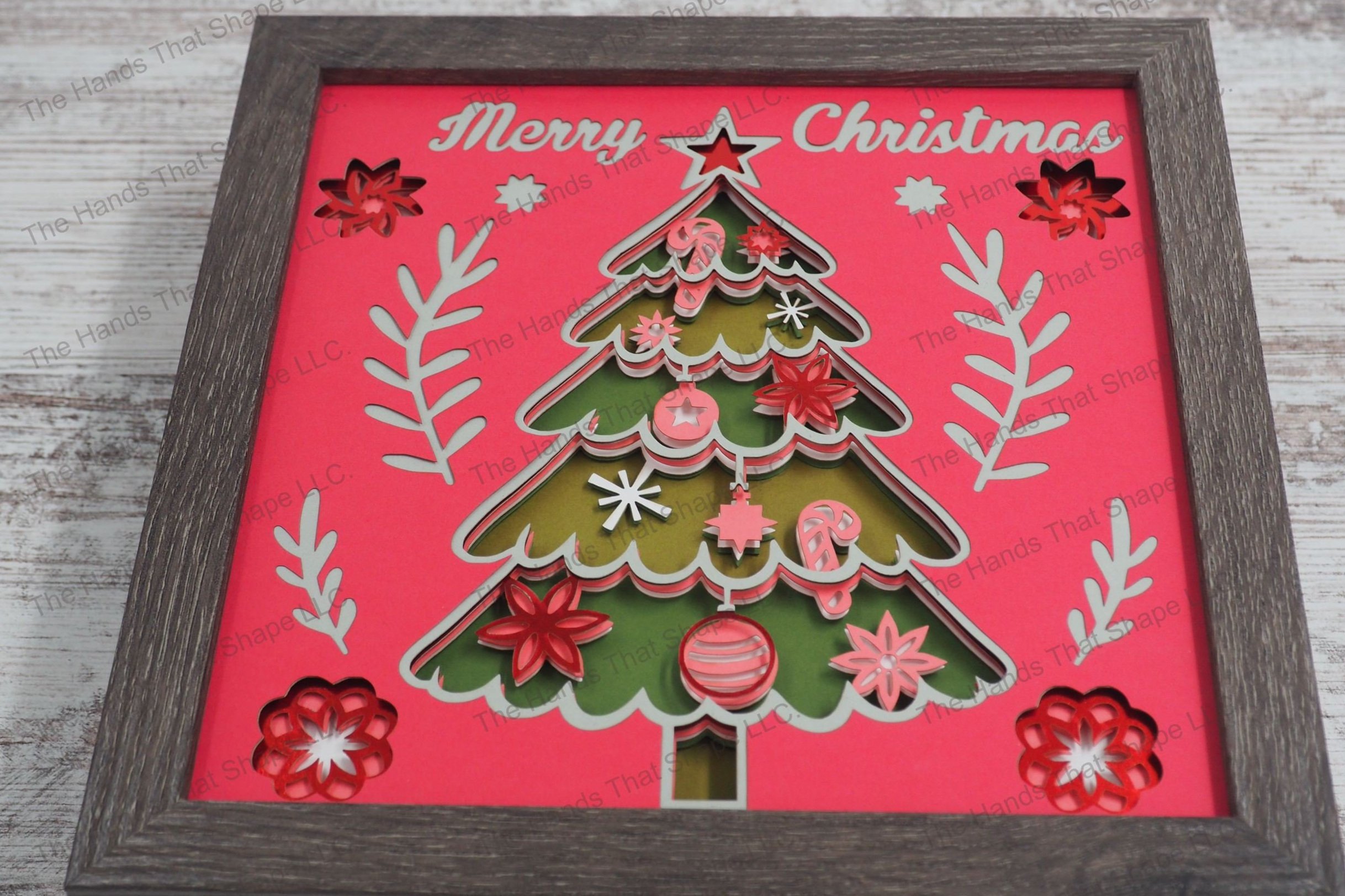 A festive layered paper shadowbox featuring a richly decorated Christmas tree with ornaments and a star topper, accompanied by the greeting 'Merry Christmas.'