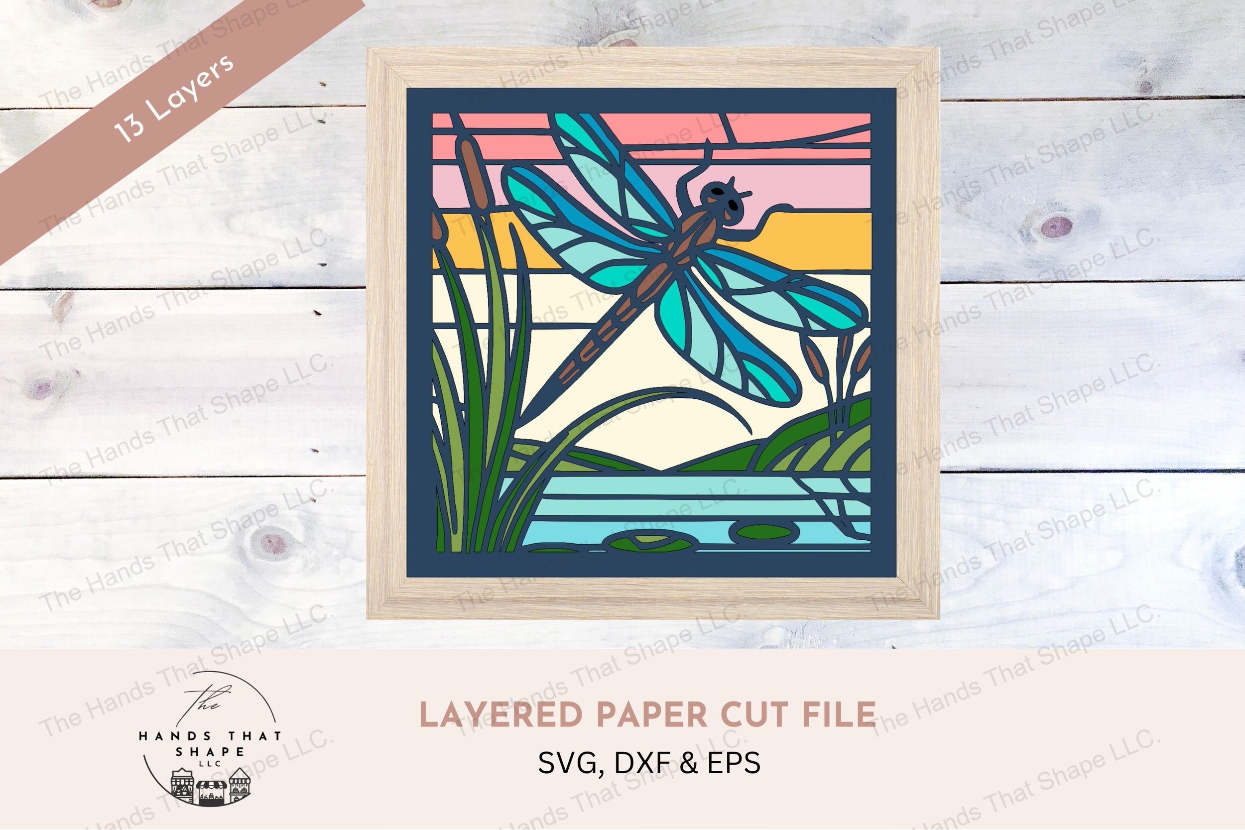 This captivating layered cardstock art piece features a dragonfly by the water's edge, surrounded by cattails and lily pads illuminated by a fresh sunrise.