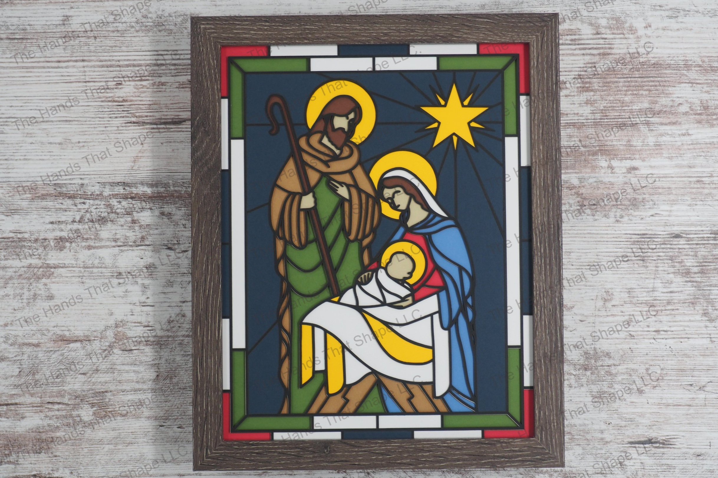 A stunning depiction of the Nativity scene crafted in a stained glass style using 10 layers of colored premium cardstock to create a vivid 3D effect.