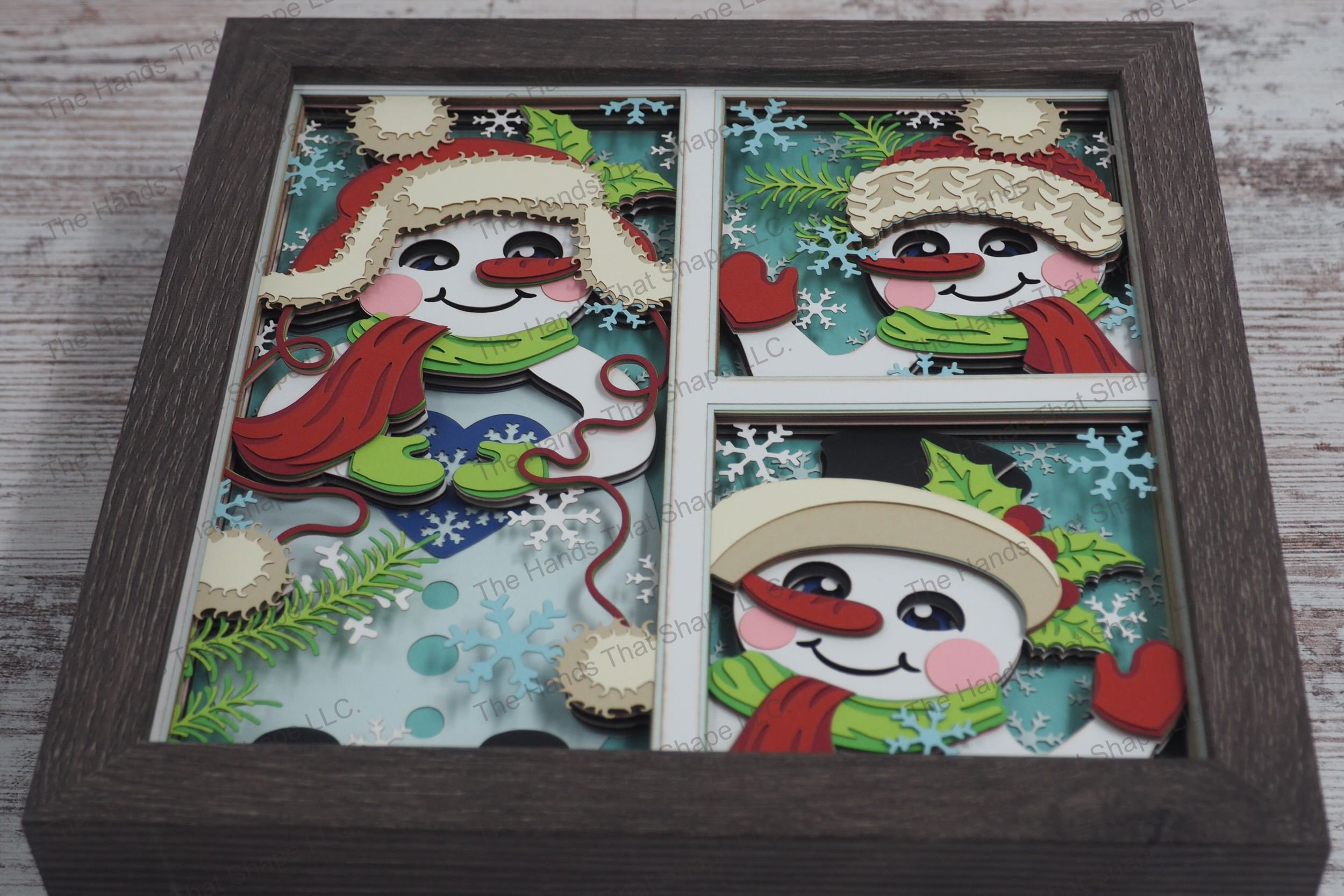 A captivating layered paper shadowbox featuring three distinct snowman scenes, each in its own window, with joyful expressions and festive accessories.