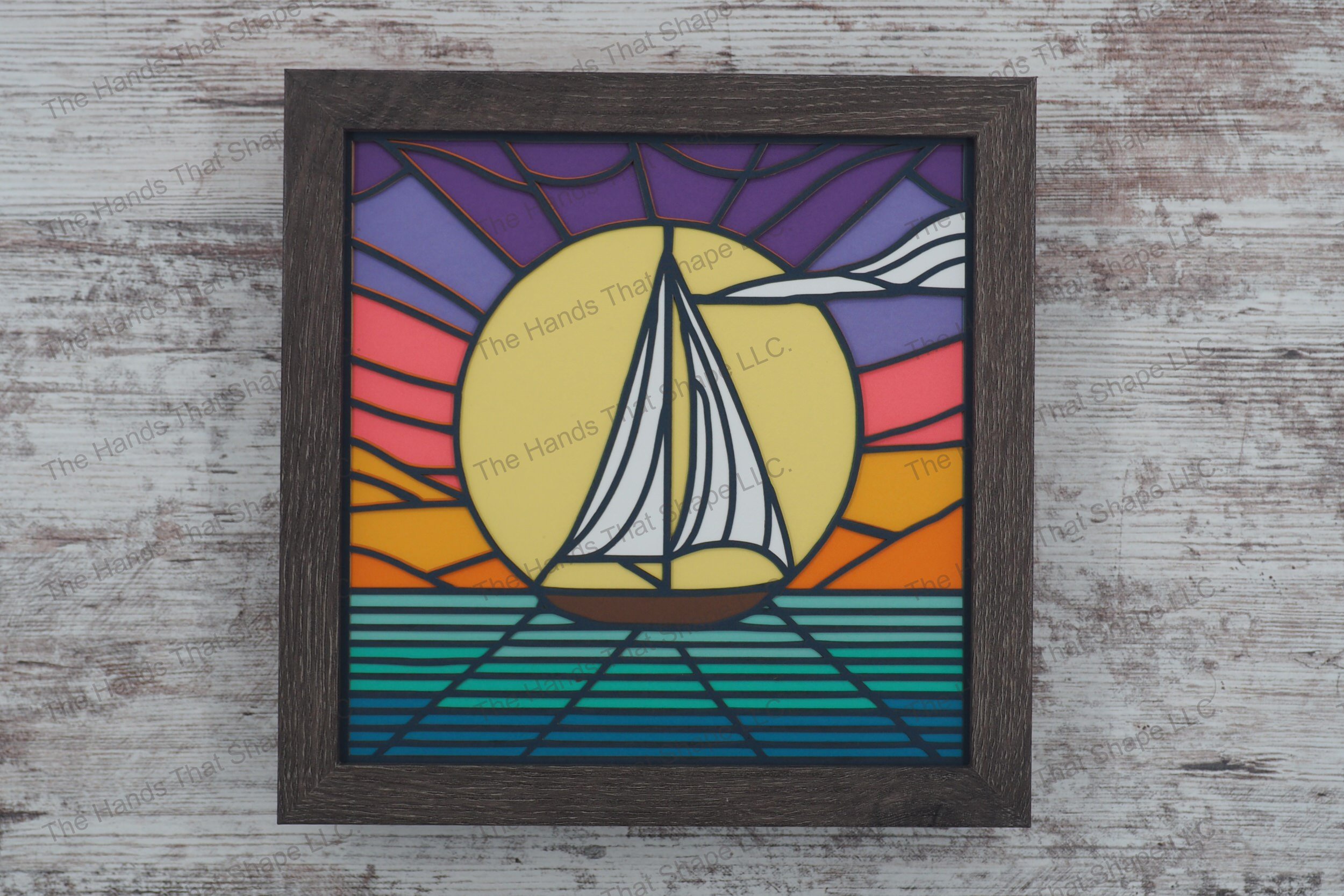 Immerse yourself in the tranquility of a sailboat gliding across a lake at sunset, captured in this layered paper shadowbox art, all beautifully framed gray MDF