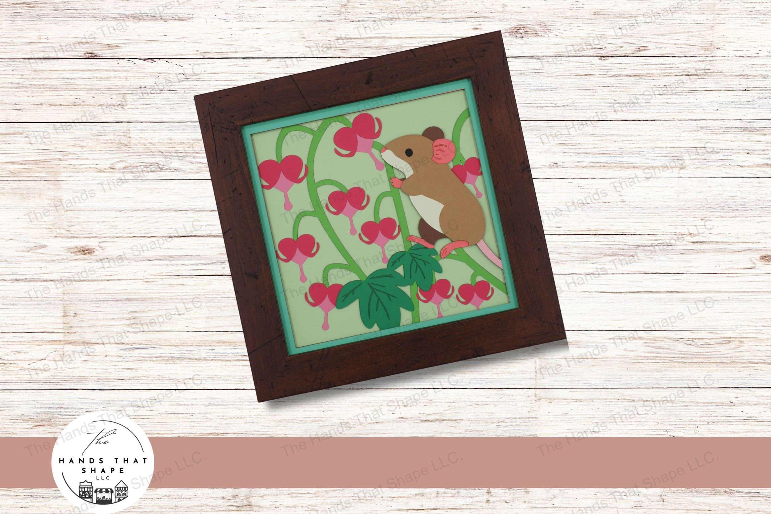 This layered cardstock art piece vividly captures a whimsical scene of a little mouse climbing a bleeding heart flower, surrounded by lush blooms.
