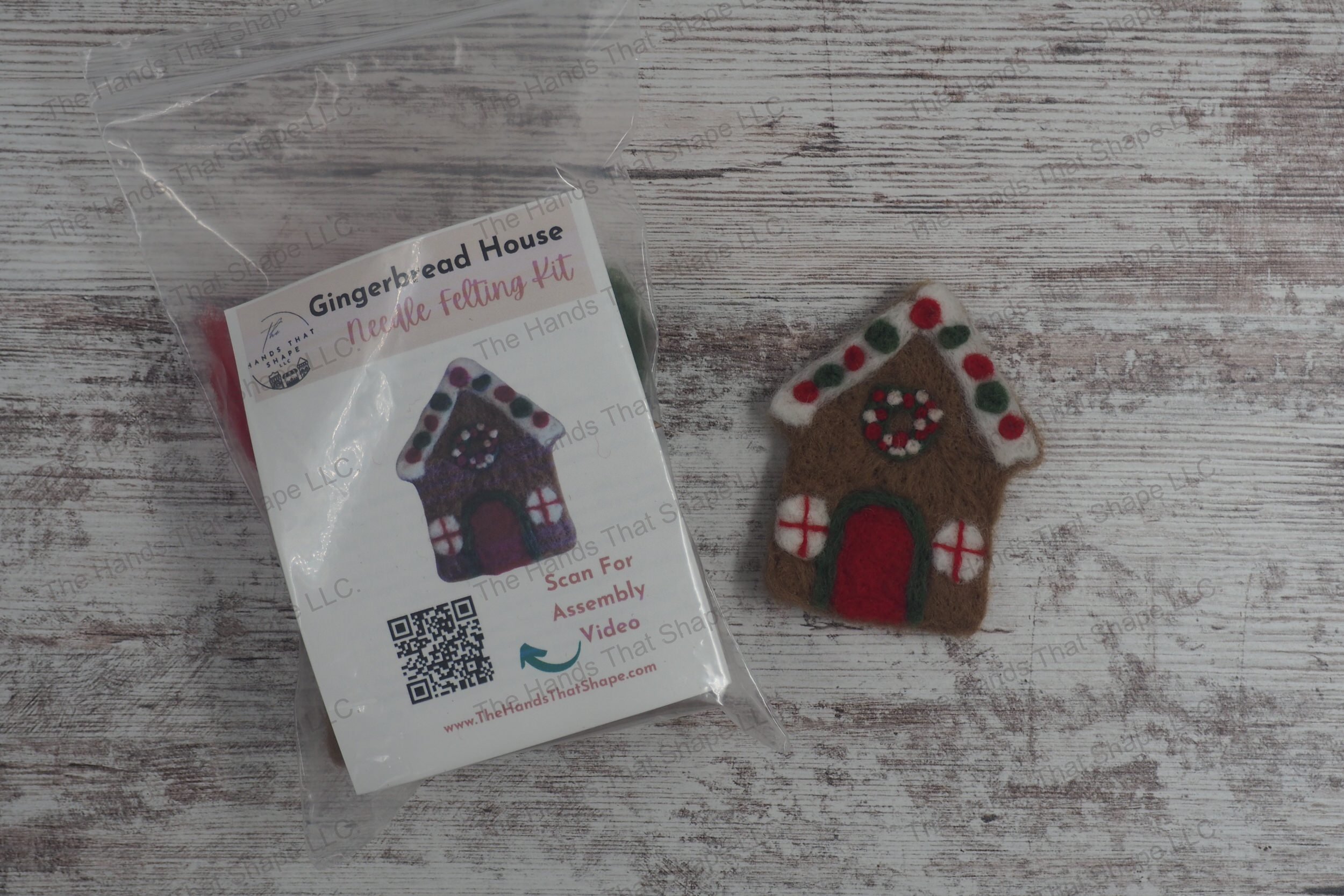 Craft a festive gingerbread house with this needle felting kit featuring colored wools, felting needles, a foam pad, and a wooden frame template.