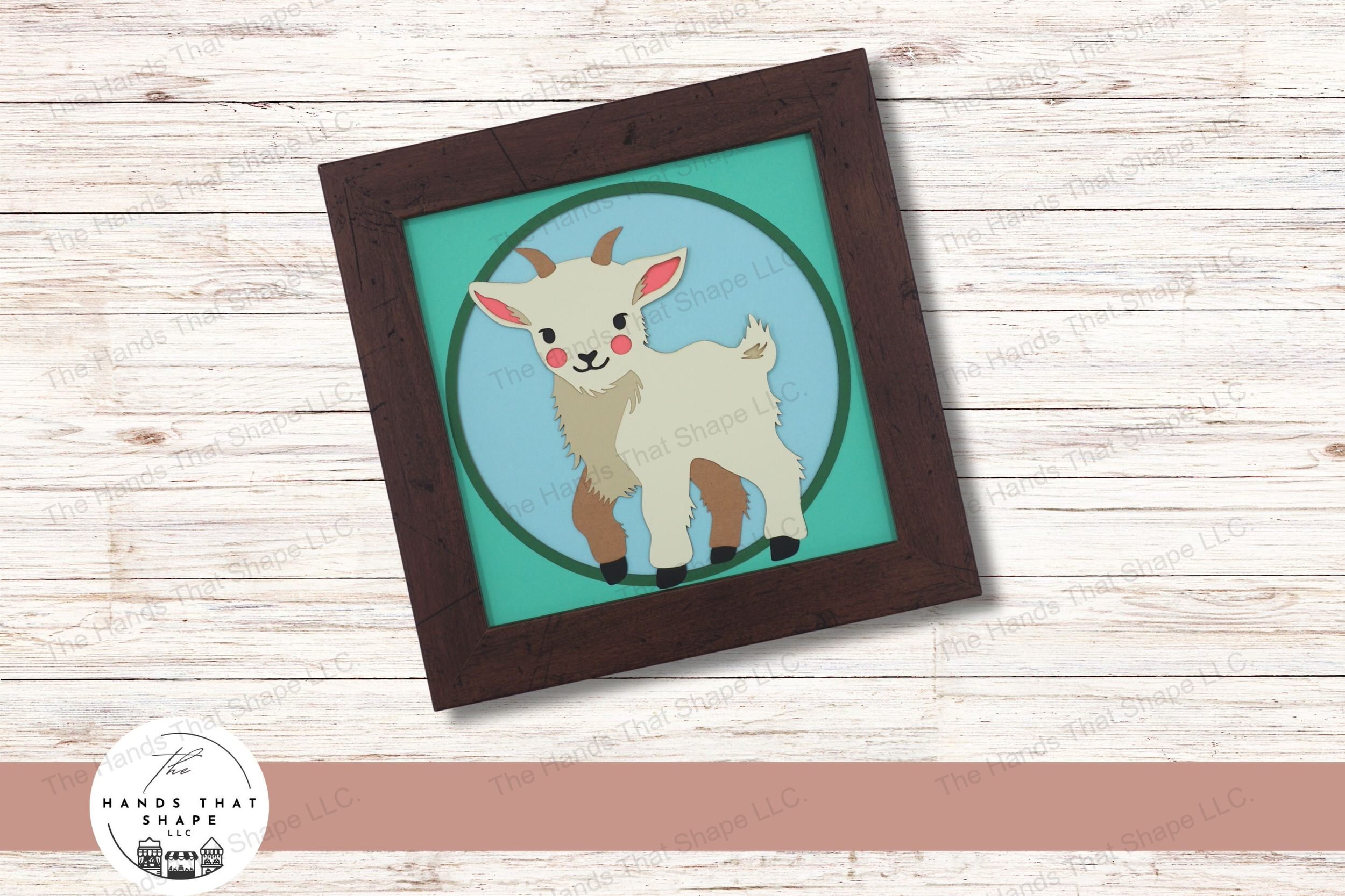 This layered cardstock art piece vividly captures a charming baby goat with rosy pink cheeks and playful horns, creating an engaging and endearing farm scene.
