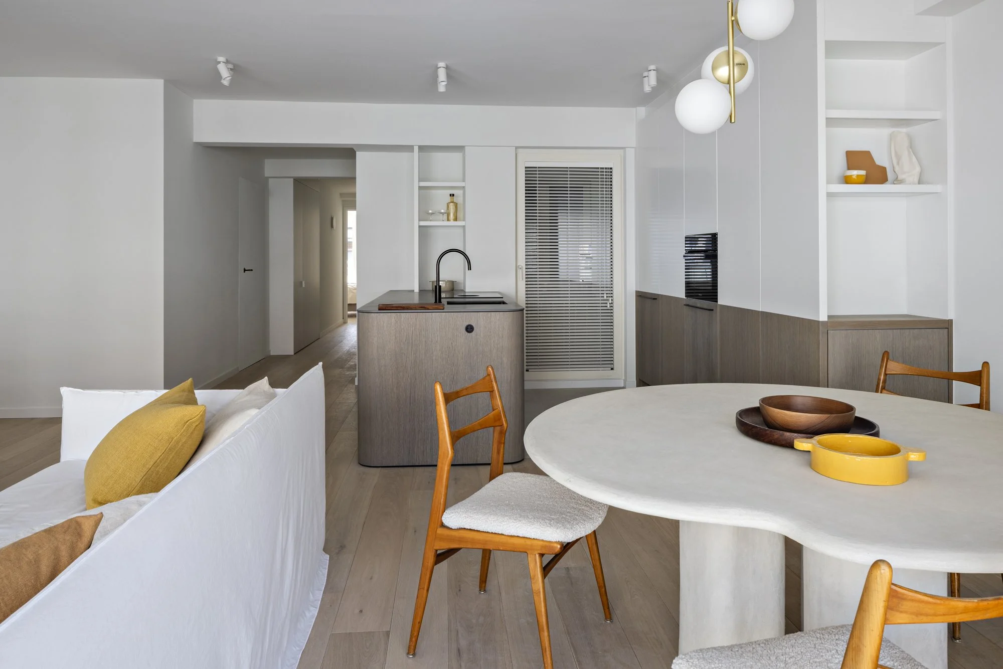 Ronde tafel met houten stoelen, schalen in het midden, neutrale inrichting.