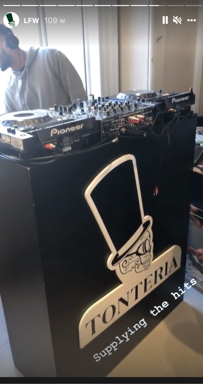 A DJ setup with Pioneer turntables and mixer on a black booth at an event, with a logo reading 'Tonteria' and a graphic of a top hat.